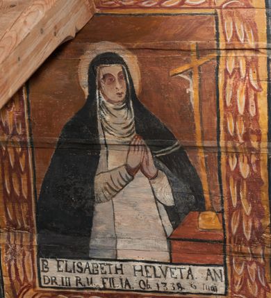 Zdjęcie nr 15: Polichromia ścienna nawy pokrywa wszystkie ściany oraz strop tej części świątyni. Polichromia figuralno-ornamentalna. W łuku tęczowym fryz podstropowy, wypełniony ornamentem w formie schematycznej, stylizowanej wici roślinnej, ujętej na krańcach uskrzydlonymi główkami anielskimi, umieszczonymi w medalionach. Poniżej fryzu, po lewej herb cesarski, ujęty w wieniec laurowy, w tle pejzaż; po przeciwnej stronie, zwieńczony insygniami biskupimi, herb biskupa Jerzego Lippay de Zongor – dwa lwy, ustawione antytetycznie przy ukoronowanej kolumnie.

Na północnej ścianie nawy do wysokości jednej trzeciej ściany pas kwater z wizerunkami świętych, ujętymi w obramienia, utworzone z ornamentu w formie silnie stylizowanej wici roślinnej. Pola pomiędzy kwaterami wypełnione schematycznym ornamentem geometryczno-figuralnym, złożonym ze skręconej wici roślinnej oraz główek anielskich. Od strony prezbiterium kolejno przedstawienia opatrzone następującymi podpisami:
„S(NCTVS) ADREAS ZOREARBUS EREMITA NITRAE / ET TRENCHINII  27 XIV LY ANNO 1609”;
„B. MATHEAI ESCANDELI NATUS BUDAE MARTIRIO AFFE/CTUS in Sinis quo infide infidelum convertendorum causa penefravit”;
„B. SADOCH ORD. PRAED. A. S. DOMINICO in UNGARIAM/ MISSUS EGREGIE LABORAVIT MARTYRIO  affectus 1260. 3. Iunii”;
„S(ANCTVS) COLOMANUS MS. MARGARITAE REGINAE SCOTIAE UNGARA/ MATRE NATAE FILIUS SUSPENSUS STOKARAVIAE COLIT 13 oct.”;
„S(ANCTVS) CAPISTRANI ORD. S. FRAC. TURCAS BELRADO FUGAVIT/ UNG. Ufilissim[us] obit 1455 23 Od. Viilaci in Ung. Sepult[us].”;
„S(ANCTVS) PETRUS THOMASIUS CARMELITA AT LUDOVICUM/ UNG. REGEM NUNTI[US] APOSTOL. De pace cum Venetis egit obit 29 9 1367”.

Kontynuacja przedstawień na ścianie zachodniej:
„B. IACOBUS PICENUS ORD. S. FRANC. S. CAPISTRANI IN UNG./ COAPOSTOL[US] MULTOS AD CHRISTI FIDEM CONVERTIT”;
„S(ANCTVS) IOANNES NEPOMUCN.”.

W górnej partii ściany północnej scena wielofiguralna: Św. Jan Chrzciciel nauczający w otoczeniu tłumu. W tle pejzaż z drzewami i  zarysowanym na najdalszym planie masywem górskim. Ponad przedstawieniem napis: „VENIT IN OMNEM REGIONEM PRAEDICANS BAPTISMUM POENITENITIAE LUCAE 3.”. Do sceny kazania św Jana Chrzciciela przylega środkowy rząd wizerunków świętych. Cztery pierwsze przedstawienia znajdują się na ścianie północnej i biegną w kierunku chóru muzycznego:
„B. BERTHODEUS (…) 17 DECE”;
„B. IOANNES DOMINICI ORD. PRAED. EP. Et. CARDIN ad. SIGISMUN. UN. BEC. NUNT. APOTOLIC. BUDAE obiit (…) 1418” [w lewym górnym rogu odnotowane białą farbą informacje o kolejnych konserwacjach polichromii];
„B. ANTONIUS UNGARUS ORD. FRANC. FULGINII/IN OBSEQUIO INFIRMORUM ob. 1398. 13 May.”;
„B. MATHAEUS ESCANDELI NATUS BUDA MARTIRIS AFFECTUS IN SINIS QUO INFIDELIUM…”.

Nad chórem muzycznym, na ścianie zachodniej znajdują się kolejne cztery wizerunki z tego cyklu:
„B. MURITIUS CSAKY ORD. PRAED AMORE IN DEIPURAM MIRACU/LIS CLARUS obiit laurmi 1336 20. Mar. [.]oii Ferr.”;
„B. MAURUS EX MANASTETRIO S. MARTINI /ORD. S. BENED. EPISC. QUINQUE ECCLESIENS in UNGARIA”;
„S(ANCTVS) BENEDICTUS MAR. EREMITA PROPE TRENCHINIUM/IN VASUM MERSUS COLITUR IM aii”;
„B. EUSEBIUS CANONICO STRIGOMI PRIMUS/PROVINCIALIS ORA: S. PAULI primi Erem: obit 1270. 20. Ian.”.

Ostatnie dwa wizerunki na ścianie południowej nad chórem muzycznym, kolejno od strony ściany tęczowej:
„S(ANCTVS) ASTRICQ ARCHIEN. COLOCENS. IN UNGARIA ORD./ s. BENEDICTI OBIIT. AN. 1034. 12 Novembris”;
„S(ANCTVS) PAULUS UNGARUS PRIMUS ORD. PRAED./ UNGARIA PROVINCIALIS MARTIRIO affectis”.

Na podniebiu zaskrzynienia kontynuacja cyklu hagiograficznego. Od łuku tęczowego, wizerunki umieszczone są między elementami ornamentacyjnym, opatrzone następującymi podpisami:
„B. GISELA S. STEPH. R. / U. CONIUX Ob. 1036”;
„S(ANCTVS) ESABETH ANDR. U. FI/LIA DUCISS THURINN ob. 1226”;
„B. GERTRUDIS V. FILIA/ S. ELISABETHAE THURING”;
„B. ELISABETH HELVETA AN/ DR III R.U. FILIA ob. 1338 6 mai”;
„B. HELENA V. ORD. PRAEDIC. OB. BUD. AN. 1720 9 nov.”;
„S(ANCTVS) MARGHARITA REGINA SCOTIAE NATA IN UNGARIA TEMORAE S. SALAMONIS”;
„B. ELISABETHU. Ord. Praed S. STEPHANI UNG. REGIS. FILIA OBIIT CIV. Anno 1285 6 martii”;
„S(ANCTA) URSULA CUM 11 000 VIRGINUM AB ATTILA INTERFECTA 1383 21 Oct.”.

Na podniebiu zaskrzynienia nad ścianą południową kontynuacja cyklu, od tęczy:
„B. MARGARITA FILIA BELAE 4 R. V. Ob. 1273. 28 Ian.”; 
„B. CUNEGUNDUDIS V. BELAE IV REG FILIA Ob. 1292. 24. 1.”.

Na ścianie południowej w dolnym pasie malowideł od strony tęczy scena figuralna z przedstawieniem św. Anny nauczającej Marię, a następnie scena piekła z przedstawieniem męki grzeszników w wypełnionej płomieniami paszczy Lewiatana. W górnej partii scena przedstawiająca pogrzeb Jana Chrzciciela. Przestrzenie wokół tego malowidła i okien szczelnie wypełnione ornamentem w formie schematycznej wici roślinnej. Drzwi pokryte dekoracją ornamentalną analogiczną do tej w przestrzeniach między obrazami w dolnym rzędzie cyklu świętych na ścianie północnej. Fryz przystropowy w całości dekorowany analogicznie jak w łuku tęczowym. 

Na stropie kontynuacja cyklu ze scenami z życia Jana Chrzciciela, rozpoczynającego się w prezbiterium. Dwa obrazy w formie prostokątów, ujęte w malowane ramy, utworzone z ornamentu złożonego z wici roślinnej i stylizowanych rozetek. Pierwsza od tęczy wielopostaciowa scena narodzin Jana Chrzciciela, w górnej partii opatrzona napisem: „QUIS PUTAS PUER ISTE ERITE IOANNES EST NOMEN EIUS LUCAE 1.”. Bliżej chóru przedstawienie Jana Chrzciciela, nauczającego na puszczy, opatrzona podpisem: „ERAT IN DESERTIS USQUE IN DIEM OSTENSIONIS SUAE LUCAE 1.”. Obrazy ujęte w iluzjonistycznie malowane kasetony z rozetami w środku. Podziały kasetonowe zaznaczone listewkami, dekorowanymi rozetkami. Pod amboną niewielkich rozmiarów malowidło, przedstawiające siedem postaci pokutujących w czyśćcu i anioła. Scena zwieńczona monogramem IHS.
