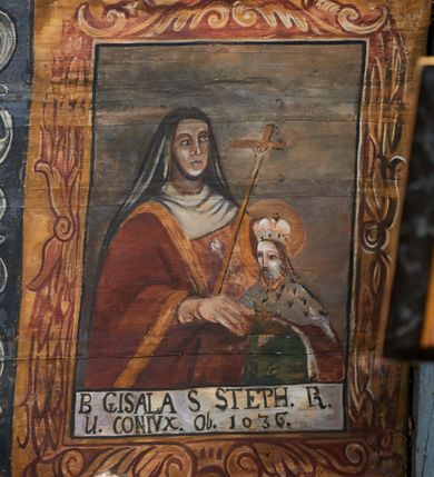 Zdjęcie nr 21: Polichromia ścienna nawy pokrywa wszystkie ściany oraz strop tej części świątyni. Polichromia figuralno-ornamentalna. W łuku tęczowym fryz podstropowy, wypełniony ornamentem w formie schematycznej, stylizowanej wici roślinnej, ujętej na krańcach uskrzydlonymi główkami anielskimi, umieszczonymi w medalionach. Poniżej fryzu, po lewej herb cesarski, ujęty w wieniec laurowy, w tle pejzaż; po przeciwnej stronie, zwieńczony insygniami biskupimi, herb biskupa Jerzego Lippay de Zongor – dwa lwy, ustawione antytetycznie przy ukoronowanej kolumnie.

Na północnej ścianie nawy do wysokości jednej trzeciej ściany pas kwater z wizerunkami świętych, ujętymi w obramienia, utworzone z ornamentu w formie silnie stylizowanej wici roślinnej. Pola pomiędzy kwaterami wypełnione schematycznym ornamentem geometryczno-figuralnym, złożonym ze skręconej wici roślinnej oraz główek anielskich. Od strony prezbiterium kolejno przedstawienia opatrzone następującymi podpisami:
„S(NCTVS) ADREAS ZOREARBUS EREMITA NITRAE / ET TRENCHINII  27 XIV LY ANNO 1609”;
„B. MATHEAI ESCANDELI NATUS BUDAE MARTIRIO AFFE/CTUS in Sinis quo infide infidelum convertendorum causa penefravit”;
„B. SADOCH ORD. PRAED. A. S. DOMINICO in UNGARIAM/ MISSUS EGREGIE LABORAVIT MARTYRIO  affectus 1260. 3. Iunii”;
„S(ANCTVS) COLOMANUS MS. MARGARITAE REGINAE SCOTIAE UNGARA/ MATRE NATAE FILIUS SUSPENSUS STOKARAVIAE COLIT 13 oct.”;
„S(ANCTVS) CAPISTRANI ORD. S. FRAC. TURCAS BELRADO FUGAVIT/ UNG. Ufilissim[us] obit 1455 23 Od. Viilaci in Ung. Sepult[us].”;
„S(ANCTVS) PETRUS THOMASIUS CARMELITA AT LUDOVICUM/ UNG. REGEM NUNTI[US] APOSTOL. De pace cum Venetis egit obit 29 9 1367”.

Kontynuacja przedstawień na ścianie zachodniej:
„B. IACOBUS PICENUS ORD. S. FRANC. S. CAPISTRANI IN UNG./ COAPOSTOL[US] MULTOS AD CHRISTI FIDEM CONVERTIT”;
„S(ANCTVS) IOANNES NEPOMUCN.”.

W górnej partii ściany północnej scena wielofiguralna: Św. Jan Chrzciciel nauczający w otoczeniu tłumu. W tle pejzaż z drzewami i  zarysowanym na najdalszym planie masywem górskim. Ponad przedstawieniem napis: „VENIT IN OMNEM REGIONEM PRAEDICANS BAPTISMUM POENITENITIAE LUCAE 3.”. Do sceny kazania św Jana Chrzciciela przylega środkowy rząd wizerunków świętych. Cztery pierwsze przedstawienia znajdują się na ścianie północnej i biegną w kierunku chóru muzycznego:
„B. BERTHODEUS (…) 17 DECE”;
„B. IOANNES DOMINICI ORD. PRAED. EP. Et. CARDIN ad. SIGISMUN. UN. BEC. NUNT. APOTOLIC. BUDAE obiit (…) 1418” [w lewym górnym rogu odnotowane białą farbą informacje o kolejnych konserwacjach polichromii];
„B. ANTONIUS UNGARUS ORD. FRANC. FULGINII/IN OBSEQUIO INFIRMORUM ob. 1398. 13 May.”;
„B. MATHAEUS ESCANDELI NATUS BUDA MARTIRIS AFFECTUS IN SINIS QUO INFIDELIUM…”.

Nad chórem muzycznym, na ścianie zachodniej znajdują się kolejne cztery wizerunki z tego cyklu:
„B. MURITIUS CSAKY ORD. PRAED AMORE IN DEIPURAM MIRACU/LIS CLARUS obiit laurmi 1336 20. Mar. [.]oii Ferr.”;
„B. MAURUS EX MANASTETRIO S. MARTINI /ORD. S. BENED. EPISC. QUINQUE ECCLESIENS in UNGARIA”;
„S(ANCTVS) BENEDICTUS MAR. EREMITA PROPE TRENCHINIUM/IN VASUM MERSUS COLITUR IM aii”;
„B. EUSEBIUS CANONICO STRIGOMI PRIMUS/PROVINCIALIS ORA: S. PAULI primi Erem: obit 1270. 20. Ian.”.

Ostatnie dwa wizerunki na ścianie południowej nad chórem muzycznym, kolejno od strony ściany tęczowej:
„S(ANCTVS) ASTRICQ ARCHIEN. COLOCENS. IN UNGARIA ORD./ s. BENEDICTI OBIIT. AN. 1034. 12 Novembris”;
„S(ANCTVS) PAULUS UNGARUS PRIMUS ORD. PRAED./ UNGARIA PROVINCIALIS MARTIRIO affectis”.

Na podniebiu zaskrzynienia kontynuacja cyklu hagiograficznego. Od łuku tęczowego, wizerunki umieszczone są między elementami ornamentacyjnym, opatrzone następującymi podpisami:
„B. GISELA S. STEPH. R. / U. CONIUX Ob. 1036”;
„S(ANCTVS) ESABETH ANDR. U. FI/LIA DUCISS THURINN ob. 1226”;
„B. GERTRUDIS V. FILIA/ S. ELISABETHAE THURING”;
„B. ELISABETH HELVETA AN/ DR III R.U. FILIA ob. 1338 6 mai”;
„B. HELENA V. ORD. PRAEDIC. OB. BUD. AN. 1720 9 nov.”;
„S(ANCTVS) MARGHARITA REGINA SCOTIAE NATA IN UNGARIA TEMORAE S. SALAMONIS”;
„B. ELISABETHU. Ord. Praed S. STEPHANI UNG. REGIS. FILIA OBIIT CIV. Anno 1285 6 martii”;
„S(ANCTA) URSULA CUM 11 000 VIRGINUM AB ATTILA INTERFECTA 1383 21 Oct.”.

Na podniebiu zaskrzynienia nad ścianą południową kontynuacja cyklu, od tęczy:
„B. MARGARITA FILIA BELAE 4 R. V. Ob. 1273. 28 Ian.”; 
„B. CUNEGUNDUDIS V. BELAE IV REG FILIA Ob. 1292. 24. 1.”.

Na ścianie południowej w dolnym pasie malowideł od strony tęczy scena figuralna z przedstawieniem św. Anny nauczającej Marię, a następnie scena piekła z przedstawieniem męki grzeszników w wypełnionej płomieniami paszczy Lewiatana. W górnej partii scena przedstawiająca pogrzeb Jana Chrzciciela. Przestrzenie wokół tego malowidła i okien szczelnie wypełnione ornamentem w formie schematycznej wici roślinnej. Drzwi pokryte dekoracją ornamentalną analogiczną do tej w przestrzeniach między obrazami w dolnym rzędzie cyklu świętych na ścianie północnej. Fryz przystropowy w całości dekorowany analogicznie jak w łuku tęczowym. 

Na stropie kontynuacja cyklu ze scenami z życia Jana Chrzciciela, rozpoczynającego się w prezbiterium. Dwa obrazy w formie prostokątów, ujęte w malowane ramy, utworzone z ornamentu złożonego z wici roślinnej i stylizowanych rozetek. Pierwsza od tęczy wielopostaciowa scena narodzin Jana Chrzciciela, w górnej partii opatrzona napisem: „QUIS PUTAS PUER ISTE ERITE IOANNES EST NOMEN EIUS LUCAE 1.”. Bliżej chóru przedstawienie Jana Chrzciciela, nauczającego na puszczy, opatrzona podpisem: „ERAT IN DESERTIS USQUE IN DIEM OSTENSIONIS SUAE LUCAE 1.”. Obrazy ujęte w iluzjonistycznie malowane kasetony z rozetami w środku. Podziały kasetonowe zaznaczone listewkami, dekorowanymi rozetkami. Pod amboną niewielkich rozmiarów malowidło, przedstawiające siedem postaci pokutujących w czyśćcu i anioła. Scena zwieńczona monogramem IHS.
