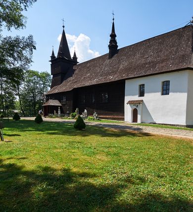 Zdjęcie nr 5: Kościół św. Jana Chrzciciela w Orawce usytuowany jest w centrum wsi na zachód od drogi prowadzącej z Jabłonki do Podwilka. Jest otoczony starodrzewiem, teren przykościelny opasany jest murem z łamanego kamienia. W granicach ogrodzenia znajduje się rozległy cmentarz przykościelny. 

Kościół orientowany, drewniany, konstrukcji zrębowej z wieżą na słup na kamiennej podmurówce. Prezbiterium wydłużone i zamknięte wielobocznie, nawa szersza i prostokątna. Przy prezbiterium od północy usytuowana jest zakrystia, a od wschodu murowana kaplica Matki Boskiej Bolesnej z 1728 roku o wielobocznym zakończeniu z przybudówką w rodzaju zakrystii od północy. Świątynia zbudowana jest z bierwion, łączonych na kwadratowy czop, bez ostatków. Poszczególne barwiona umocnione są pionowo tyblami. 

Wnętrze kościoła nakrywają stropy drewniane, płaskie, w nawie z zaskrzynieniami, podpartymi słupami. Zaskrzynienia w nawie obite są deskami dekorowanymi polichromią. W kaplicy Matki Boskiej Bolesnej sklepienie kolebkowe z lunetami. Ściana arkady tęczowej zamknięta jest łukiem półkolistym, na belce tęczowej umieszczona jest Grupa Ukrzyżowania. Przy nawie od południa dobudowana jest nowsza, drewniana kruchta. Chór muzyczny wsparty na dwóch profilowanych słupach z nim złączony chórek boczny przy północnej ścianie nawy. Otwory okienne usytuowane wyłącznie od strony południowej w kształcie stojących prostokątów, zamknięte półkoliście.

Na zewnątrz ściany świątyni obite gontem z wyjątkiem murowanej kaplicy Matki Boskiej Bolesnej, która została otynkowana. Wieża częściowo wtopiona w korpus, częściowo wysunięta ryzalitycznie; w przyziemiu babiniec. Wieża wzniesiona w konstrukcji słupowo-ramowej, główne narożne słupy nośne pochylone, wzmocnione tzw. krzyżami św. Andrzeja. Wieża zwieńczona jest nadwieszoną izbicą, szalowaną deskami w układzie pionowym z listwowaniem z czterolistnymi okienkami. Wyżej ostrosłupowy hełm z czterema narożnymi wieżyczkami. Kościół nakryty gontem w postaci długiego, kalenicowego dachu o rozległych połaciach, otulonym płaszczem gontowym z szerokim, załamanym okapem. Na wspólnym dachu kościoła i kaplicy nowa wieżyczka na sygnaturkę. 