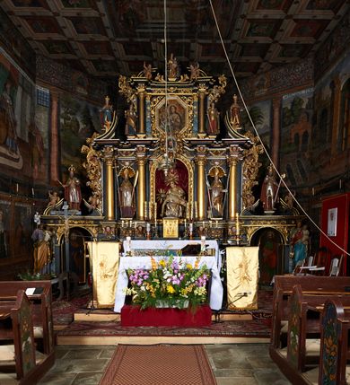 Zdjęcie nr 6: Kościół św. Jana Chrzciciela w Orawce usytuowany jest w centrum wsi na zachód od drogi prowadzącej z Jabłonki do Podwilka. Jest otoczony starodrzewiem, teren przykościelny opasany jest murem z łamanego kamienia. W granicach ogrodzenia znajduje się rozległy cmentarz przykościelny. 

Kościół orientowany, drewniany, konstrukcji zrębowej z wieżą na słup na kamiennej podmurówce. Prezbiterium wydłużone i zamknięte wielobocznie, nawa szersza i prostokątna. Przy prezbiterium od północy usytuowana jest zakrystia, a od wschodu murowana kaplica Matki Boskiej Bolesnej z 1728 roku o wielobocznym zakończeniu z przybudówką w rodzaju zakrystii od północy. Świątynia zbudowana jest z bierwion, łączonych na kwadratowy czop, bez ostatków. Poszczególne barwiona umocnione są pionowo tyblami. 

Wnętrze kościoła nakrywają stropy drewniane, płaskie, w nawie z zaskrzynieniami, podpartymi słupami. Zaskrzynienia w nawie obite są deskami dekorowanymi polichromią. W kaplicy Matki Boskiej Bolesnej sklepienie kolebkowe z lunetami. Ściana arkady tęczowej zamknięta jest łukiem półkolistym, na belce tęczowej umieszczona jest Grupa Ukrzyżowania. Przy nawie od południa dobudowana jest nowsza, drewniana kruchta. Chór muzyczny wsparty na dwóch profilowanych słupach z nim złączony chórek boczny przy północnej ścianie nawy. Otwory okienne usytuowane wyłącznie od strony południowej w kształcie stojących prostokątów, zamknięte półkoliście.

Na zewnątrz ściany świątyni obite gontem z wyjątkiem murowanej kaplicy Matki Boskiej Bolesnej, która została otynkowana. Wieża częściowo wtopiona w korpus, częściowo wysunięta ryzalitycznie; w przyziemiu babiniec. Wieża wzniesiona w konstrukcji słupowo-ramowej, główne narożne słupy nośne pochylone, wzmocnione tzw. krzyżami św. Andrzeja. Wieża zwieńczona jest nadwieszoną izbicą, szalowaną deskami w układzie pionowym z listwowaniem z czterolistnymi okienkami. Wyżej ostrosłupowy hełm z czterema narożnymi wieżyczkami. Kościół nakryty gontem w postaci długiego, kalenicowego dachu o rozległych połaciach, otulonym płaszczem gontowym z szerokim, załamanym okapem. Na wspólnym dachu kościoła i kaplicy nowa wieżyczka na sygnaturkę. 