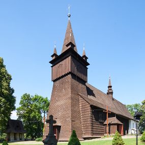 Zdjęcie nr 1: Kościół św. Jana Chrzciciela w Orawce usytuowany jest w centrum wsi na zachód od drogi prowadzącej z Jabłonki do Podwilka. Jest otoczony starodrzewiem, teren przykościelny opasany jest murem z łamanego kamienia. W granicach ogrodzenia znajduje się rozległy cmentarz przykościelny. 

Kościół orientowany, drewniany, konstrukcji zrębowej z wieżą na słup na kamiennej podmurówce. Prezbiterium wydłużone i zamknięte wielobocznie, nawa szersza i prostokątna. Przy prezbiterium od północy usytuowana jest zakrystia, a od wschodu murowana kaplica Matki Boskiej Bolesnej z 1728 roku o wielobocznym zakończeniu z przybudówką w rodzaju zakrystii od północy. Świątynia zbudowana jest z bierwion, łączonych na kwadratowy czop, bez ostatków. Poszczególne barwiona umocnione są pionowo tyblami. 

Wnętrze kościoła nakrywają stropy drewniane, płaskie, w nawie z zaskrzynieniami, podpartymi słupami. Zaskrzynienia w nawie obite są deskami dekorowanymi polichromią. W kaplicy Matki Boskiej Bolesnej sklepienie kolebkowe z lunetami. Ściana arkady tęczowej zamknięta jest łukiem półkolistym, na belce tęczowej umieszczona jest Grupa Ukrzyżowania. Przy nawie od południa dobudowana jest nowsza, drewniana kruchta. Chór muzyczny wsparty na dwóch profilowanych słupach z nim złączony chórek boczny przy północnej ścianie nawy. Otwory okienne usytuowane wyłącznie od strony południowej w kształcie stojących prostokątów, zamknięte półkoliście.

Na zewnątrz ściany świątyni obite gontem z wyjątkiem murowanej kaplicy Matki Boskiej Bolesnej, która została otynkowana. Wieża częściowo wtopiona w korpus, częściowo wysunięta ryzalitycznie; w przyziemiu babiniec. Wieża wzniesiona w konstrukcji słupowo-ramowej, główne narożne słupy nośne pochylone, wzmocnione tzw. krzyżami św. Andrzeja. Wieża zwieńczona jest nadwieszoną izbicą, szalowaną deskami w układzie pionowym z listwowaniem z czterolistnymi okienkami. Wyżej ostrosłupowy hełm z czterema narożnymi wieżyczkami. Kościół nakryty gontem w postaci długiego, kalenicowego dachu o rozległych połaciach, otulonym płaszczem gontowym z szerokim, załamanym okapem. Na wspólnym dachu kościoła i kaplicy nowa wieżyczka na sygnaturkę. 