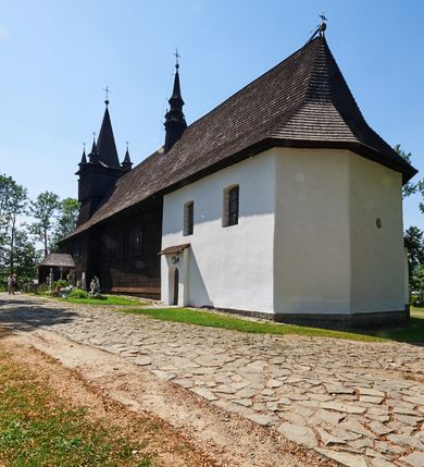 Zdjęcie nr 4: Kościół św. Jana Chrzciciela w Orawce usytuowany jest w centrum wsi na zachód od drogi prowadzącej z Jabłonki do Podwilka. Jest otoczony starodrzewiem, teren przykościelny opasany jest murem z łamanego kamienia. W granicach ogrodzenia znajduje się rozległy cmentarz przykościelny. 

Kościół orientowany, drewniany, konstrukcji zrębowej z wieżą na słup na kamiennej podmurówce. Prezbiterium wydłużone i zamknięte wielobocznie, nawa szersza i prostokątna. Przy prezbiterium od północy usytuowana jest zakrystia, a od wschodu murowana kaplica Matki Boskiej Bolesnej z 1728 roku o wielobocznym zakończeniu z przybudówką w rodzaju zakrystii od północy. Świątynia zbudowana jest z bierwion, łączonych na kwadratowy czop, bez ostatków. Poszczególne barwiona umocnione są pionowo tyblami. 

Wnętrze kościoła nakrywają stropy drewniane, płaskie, w nawie z zaskrzynieniami, podpartymi słupami. Zaskrzynienia w nawie obite są deskami dekorowanymi polichromią. W kaplicy Matki Boskiej Bolesnej sklepienie kolebkowe z lunetami. Ściana arkady tęczowej zamknięta jest łukiem półkolistym, na belce tęczowej umieszczona jest Grupa Ukrzyżowania. Przy nawie od południa dobudowana jest nowsza, drewniana kruchta. Chór muzyczny wsparty na dwóch profilowanych słupach z nim złączony chórek boczny przy północnej ścianie nawy. Otwory okienne usytuowane wyłącznie od strony południowej w kształcie stojących prostokątów, zamknięte półkoliście.

Na zewnątrz ściany świątyni obite gontem z wyjątkiem murowanej kaplicy Matki Boskiej Bolesnej, która została otynkowana. Wieża częściowo wtopiona w korpus, częściowo wysunięta ryzalitycznie; w przyziemiu babiniec. Wieża wzniesiona w konstrukcji słupowo-ramowej, główne narożne słupy nośne pochylone, wzmocnione tzw. krzyżami św. Andrzeja. Wieża zwieńczona jest nadwieszoną izbicą, szalowaną deskami w układzie pionowym z listwowaniem z czterolistnymi okienkami. Wyżej ostrosłupowy hełm z czterema narożnymi wieżyczkami. Kościół nakryty gontem w postaci długiego, kalenicowego dachu o rozległych połaciach, otulonym płaszczem gontowym z szerokim, załamanym okapem. Na wspólnym dachu kościoła i kaplicy nowa wieżyczka na sygnaturkę. 