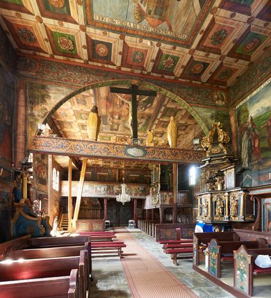 Zdjęcie nr 17: Kościół św. Jana Chrzciciela w Orawce usytuowany jest w centrum wsi na zachód od drogi prowadzącej z Jabłonki do Podwilka. Jest otoczony starodrzewiem, teren przykościelny opasany jest murem z łamanego kamienia. W granicach ogrodzenia znajduje się rozległy cmentarz przykościelny. 

Kościół orientowany, drewniany, konstrukcji zrębowej z wieżą na słup na kamiennej podmurówce. Prezbiterium wydłużone i zamknięte wielobocznie, nawa szersza i prostokątna. Przy prezbiterium od północy usytuowana jest zakrystia, a od wschodu murowana kaplica Matki Boskiej Bolesnej z 1728 roku o wielobocznym zakończeniu z przybudówką w rodzaju zakrystii od północy. Świątynia zbudowana jest z bierwion, łączonych na kwadratowy czop, bez ostatków. Poszczególne barwiona umocnione są pionowo tyblami. 

Wnętrze kościoła nakrywają stropy drewniane, płaskie, w nawie z zaskrzynieniami, podpartymi słupami. Zaskrzynienia w nawie obite są deskami dekorowanymi polichromią. W kaplicy Matki Boskiej Bolesnej sklepienie kolebkowe z lunetami. Ściana arkady tęczowej zamknięta jest łukiem półkolistym, na belce tęczowej umieszczona jest Grupa Ukrzyżowania. Przy nawie od południa dobudowana jest nowsza, drewniana kruchta. Chór muzyczny wsparty na dwóch profilowanych słupach z nim złączony chórek boczny przy północnej ścianie nawy. Otwory okienne usytuowane wyłącznie od strony południowej w kształcie stojących prostokątów, zamknięte półkoliście.

Na zewnątrz ściany świątyni obite gontem z wyjątkiem murowanej kaplicy Matki Boskiej Bolesnej, która została otynkowana. Wieża częściowo wtopiona w korpus, częściowo wysunięta ryzalitycznie; w przyziemiu babiniec. Wieża wzniesiona w konstrukcji słupowo-ramowej, główne narożne słupy nośne pochylone, wzmocnione tzw. krzyżami św. Andrzeja. Wieża zwieńczona jest nadwieszoną izbicą, szalowaną deskami w układzie pionowym z listwowaniem z czterolistnymi okienkami. Wyżej ostrosłupowy hełm z czterema narożnymi wieżyczkami. Kościół nakryty gontem w postaci długiego, kalenicowego dachu o rozległych połaciach, otulonym płaszczem gontowym z szerokim, załamanym okapem. Na wspólnym dachu kościoła i kaplicy nowa wieżyczka na sygnaturkę. 