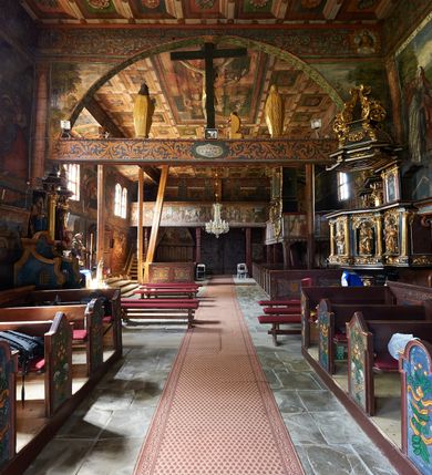 Zdjęcie nr 19: Kościół św. Jana Chrzciciela w Orawce usytuowany jest w centrum wsi na zachód od drogi prowadzącej z Jabłonki do Podwilka. Jest otoczony starodrzewiem, teren przykościelny opasany jest murem z łamanego kamienia. W granicach ogrodzenia znajduje się rozległy cmentarz przykościelny. 

Kościół orientowany, drewniany, konstrukcji zrębowej z wieżą na słup na kamiennej podmurówce. Prezbiterium wydłużone i zamknięte wielobocznie, nawa szersza i prostokątna. Przy prezbiterium od północy usytuowana jest zakrystia, a od wschodu murowana kaplica Matki Boskiej Bolesnej z 1728 roku o wielobocznym zakończeniu z przybudówką w rodzaju zakrystii od północy. Świątynia zbudowana jest z bierwion, łączonych na kwadratowy czop, bez ostatków. Poszczególne barwiona umocnione są pionowo tyblami. 

Wnętrze kościoła nakrywają stropy drewniane, płaskie, w nawie z zaskrzynieniami, podpartymi słupami. Zaskrzynienia w nawie obite są deskami dekorowanymi polichromią. W kaplicy Matki Boskiej Bolesnej sklepienie kolebkowe z lunetami. Ściana arkady tęczowej zamknięta jest łukiem półkolistym, na belce tęczowej umieszczona jest Grupa Ukrzyżowania. Przy nawie od południa dobudowana jest nowsza, drewniana kruchta. Chór muzyczny wsparty na dwóch profilowanych słupach z nim złączony chórek boczny przy północnej ścianie nawy. Otwory okienne usytuowane wyłącznie od strony południowej w kształcie stojących prostokątów, zamknięte półkoliście.

Na zewnątrz ściany świątyni obite gontem z wyjątkiem murowanej kaplicy Matki Boskiej Bolesnej, która została otynkowana. Wieża częściowo wtopiona w korpus, częściowo wysunięta ryzalitycznie; w przyziemiu babiniec. Wieża wzniesiona w konstrukcji słupowo-ramowej, główne narożne słupy nośne pochylone, wzmocnione tzw. krzyżami św. Andrzeja. Wieża zwieńczona jest nadwieszoną izbicą, szalowaną deskami w układzie pionowym z listwowaniem z czterolistnymi okienkami. Wyżej ostrosłupowy hełm z czterema narożnymi wieżyczkami. Kościół nakryty gontem w postaci długiego, kalenicowego dachu o rozległych połaciach, otulonym płaszczem gontowym z szerokim, załamanym okapem. Na wspólnym dachu kościoła i kaplicy nowa wieżyczka na sygnaturkę. 