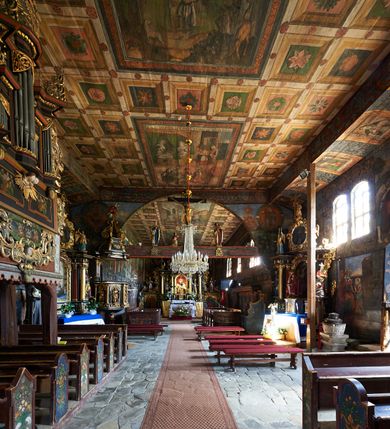 Zdjęcie nr 21: Kościół św. Jana Chrzciciela w Orawce usytuowany jest w centrum wsi na zachód od drogi prowadzącej z Jabłonki do Podwilka. Jest otoczony starodrzewiem, teren przykościelny opasany jest murem z łamanego kamienia. W granicach ogrodzenia znajduje się rozległy cmentarz przykościelny. 

Kościół orientowany, drewniany, konstrukcji zrębowej z wieżą na słup na kamiennej podmurówce. Prezbiterium wydłużone i zamknięte wielobocznie, nawa szersza i prostokątna. Przy prezbiterium od północy usytuowana jest zakrystia, a od wschodu murowana kaplica Matki Boskiej Bolesnej z 1728 roku o wielobocznym zakończeniu z przybudówką w rodzaju zakrystii od północy. Świątynia zbudowana jest z bierwion, łączonych na kwadratowy czop, bez ostatków. Poszczególne barwiona umocnione są pionowo tyblami. 

Wnętrze kościoła nakrywają stropy drewniane, płaskie, w nawie z zaskrzynieniami, podpartymi słupami. Zaskrzynienia w nawie obite są deskami dekorowanymi polichromią. W kaplicy Matki Boskiej Bolesnej sklepienie kolebkowe z lunetami. Ściana arkady tęczowej zamknięta jest łukiem półkolistym, na belce tęczowej umieszczona jest Grupa Ukrzyżowania. Przy nawie od południa dobudowana jest nowsza, drewniana kruchta. Chór muzyczny wsparty na dwóch profilowanych słupach z nim złączony chórek boczny przy północnej ścianie nawy. Otwory okienne usytuowane wyłącznie od strony południowej w kształcie stojących prostokątów, zamknięte półkoliście.

Na zewnątrz ściany świątyni obite gontem z wyjątkiem murowanej kaplicy Matki Boskiej Bolesnej, która została otynkowana. Wieża częściowo wtopiona w korpus, częściowo wysunięta ryzalitycznie; w przyziemiu babiniec. Wieża wzniesiona w konstrukcji słupowo-ramowej, główne narożne słupy nośne pochylone, wzmocnione tzw. krzyżami św. Andrzeja. Wieża zwieńczona jest nadwieszoną izbicą, szalowaną deskami w układzie pionowym z listwowaniem z czterolistnymi okienkami. Wyżej ostrosłupowy hełm z czterema narożnymi wieżyczkami. Kościół nakryty gontem w postaci długiego, kalenicowego dachu o rozległych połaciach, otulonym płaszczem gontowym z szerokim, załamanym okapem. Na wspólnym dachu kościoła i kaplicy nowa wieżyczka na sygnaturkę. 