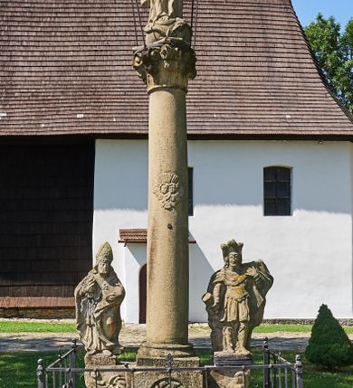 Zdjęcie nr 6: Kapliczka ustawiona na niskim prostopadłościennym postumencie. Pośrodku na wysokim cokole umieszczona kolumna, na której szczycie ustawiona jest figura Matki Boskiej Niepokalanie Poczętej z Dzieciątkiem. Cokół flankowany szerokimi spływami wolutowymi, na których ustawione są na niskich podstawach rzeźby: po lewej św. Donata, a po prawej św. Floriana. Na przedniej ściance cokołu znajduje się płaskorzeźba św. Marii Magdaleny ujęta płyciną w kształcie stojącego prostokąta, zamkniętego łukiem nadwieszonym z uskokami. Święta ukazana jest na tle groty, zwrócona trzy czwarte w prawo z rozpuszczonymi włosami, z dyscypliną w dłoni. Po lewej stronie kompozycji znajduje się wysoki, prosty krzyż i czaszka. Nad płyciną napis „ANNO D(OMI)NI 1758 / S(ANCTA) MARIA MAGDALENA / Zda SPPIPM”. Na tylnej ściance cokołu rzeźba św. Rozalii, ukazana w podobnym ujęciu z napisem „SANCTA ROSALIA VIRGO”. Święty Donat ukazany w postawie stojącej w delikatnym kontrapoście z księgą w lewej dłoni i trójzębem w prawej. Ubrany jest w strój biskupi: albę, komżę, kapę, infułę, rękawice i buty. Ma szeroką twarz, okoloną krótką brodą, bujne i długie włosy spływające na plecy. Na podstawie napis: „S(ANCTUS) DONATUS”. Po prawej stronie kolumny rzeźba św. Floriana, ustawionego frontalnie, który prawą ręką polewa wodą płonący dom, a lewą podtrzymuje u ramienia połę płaszcza. Ubrany jest w strój legionisty rzymskiego z hełmem o wyraźnie podkreślonym pióropuszu. Twarz szeroka, okolona średniej długości włosami, schowanymi pod hełmem. Podstawa pod rzeźbą opleciona metalowymi ściskami. Kolumna ustawiona na bazie, trzon gładki, dekorowany w połowie wysokości dwiema uskrzydlonymi główkami aniołów na tle promienistej glorii, kapitel koryncki. Rzeźba Matki Boskiej Niepokalanej z Dzieciątkiem na prawym ręku ustawiona jest frontalnie, w delikatnym kontrapoście na globie ziemskim, oplecionym przez węża. Maria ubrana jest w długą suknię i silnie drapowany płaszcz. Twarz owalna, okolona bujnymi i długimi włosami. Dzieciątko zwrócone jest w stronę Matki Boskiej. Rzeźba Marii osłonięta jest metalowym daszkiem wspartym na czterech prętach przytwierdzonych do metalowej opaski oplatającej kapitel kolumny. Kapliczka obwiedziona metalowym płotkiem. 

