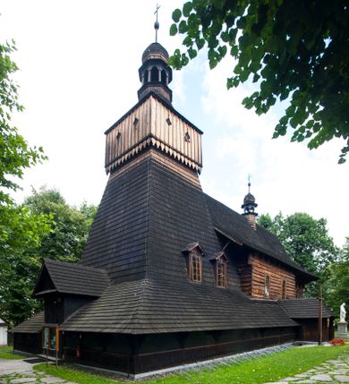 Zdjęcie nr 1: Drewniany kościół pw. św. Marcina w Jawiszowicach jest budowlą orientowaną, wzniesioną na zrąb. Do węższego prezbiterium zamkniętego trójbocznie przylega szersza nawa na rzucie zbliżonym do kwadratu. Od północy przy prezbiterium wybudowano zakrystię na planie wydłużonego prostokąta, a od zachodu wieżę w konstrukcji na słup na rzucie kwadratu. Zwieńczono ją izbicą z baniastym hełmem z latarnią. W przyziemiu wieży urządzono kruchtę. Nawę z prezbiterium nakryto jednokalenicowym dachem z więźbą w układzie storczykowym z przypustnicami (nadbitkami). W węższej części prezbiterialnej dach wsparty jest na trójkątnych zastrzałach widocznych na zewnątrz. Nad prezbiterium wznosi się sygnaturka w formie latarni z baniastym hełmem zwieńczonym krzyżem. Bryłę kościoła w całości otaczają arkadowe soboty z drewnianymi parapetami i z prześwitami wypełnionymi półprzeźroczystą pleksą. Na wysokości wejścia południowego do kościoła linię sobót wysunięto do przodu, dzięki czemu powstała pseudokruchta nakryta dachem siodłowym. Zarówno dach kościoła, jak i zakrystii, sobót oraz hełmy wieży i sygnaturki pokryte są gontem. Ściany nawy i prezbiterium utworzone z poziomo układanych bali przepruwają prostokątne okna z wpisanym łukiem półokrągłym, stanowiącym część stolarki okiennej. Na osi prezbiterium za ołtarzem głównym wycięto okulus. Wnętrze kościoła w nawie nakrywa płaski strop ze skośnym szalowaniem po bokach, a w prezbiterium pozorne sklepienie kolebkowe. Prezbiterium od nawy oddziela półokrągła tęcza z profilowaną belką, na której umieszczono grupę Ukrzyżowania. Całość wnętrza zdobi wielobarwna, ornamentalno-figuralna polichromia. Podłogę świątyni wyłożono kamiennymi płytami. W zachodniej części nawy urządzono chór muzyczny wsparty na dwóch drewnianych filarach z klatką schodową usytuowaną w południowo-zachodnim narożniku. Na chórze ustawiono prospekt organowy. Do wnętrza kościoła prowadzą dwa wejścia - od zachodu poprzez kruchtę w przyziemiu wieży oraz od południa z drewnianym portalem zamkniętym łukiem odcinkowym. Drewniany portal zamknięty łukiem odcinkowym prowadzi także z prezbiterium do zakrystii. Wypełniają go obite metalowymi płycinami i listwami drzwi. Własne wejście na zewnątrz posiada także zakrystia. Wnętrze prezbiterium w części wschodniej wypełnia architektoniczny ołtarz główny. Na ścianie północnej prezbiterium przy łuku tęczowym zawieszono ambonę, do której schody prowadzą z zakrystii. Pod skosem po obu stronach łuku tęczowego w narożnikach nawy ustawiono dwa ołtarze boczne, a pod chórem muzycznym dwa konfesjonały. W nawie stoją dwa rzędy ław kościelnych, a na jej ścianie północnej zawieszono na półeczkach feretrony procesyjne. Kościół otacza droga procesyjna wyłożona kamiennymi płytami, a cmentarz przykościelny zamyka drewniany parkan z dwiema bramkami wejściowymi.    