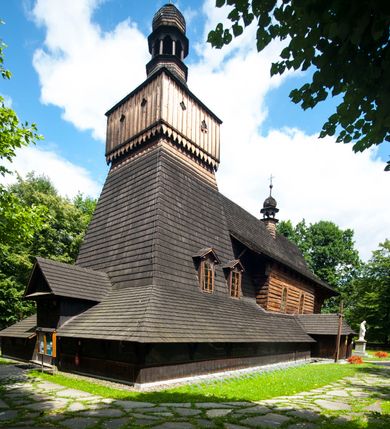 Zdjęcie nr 2: Drewniany kościół pw. św. Marcina w Jawiszowicach jest budowlą orientowaną, wzniesioną na zrąb. Do węższego prezbiterium zamkniętego trójbocznie przylega szersza nawa na rzucie zbliżonym do kwadratu. Od północy przy prezbiterium wybudowano zakrystię na planie wydłużonego prostokąta, a od zachodu wieżę w konstrukcji na słup na rzucie kwadratu. Zwieńczono ją izbicą z baniastym hełmem z latarnią. W przyziemiu wieży urządzono kruchtę. Nawę z prezbiterium nakryto jednokalenicowym dachem z więźbą w układzie storczykowym z przypustnicami (nadbitkami). W węższej części prezbiterialnej dach wsparty jest na trójkątnych zastrzałach widocznych na zewnątrz. Nad prezbiterium wznosi się sygnaturka w formie latarni z baniastym hełmem zwieńczonym krzyżem. Bryłę kościoła w całości otaczają arkadowe soboty z drewnianymi parapetami i z prześwitami wypełnionymi półprzeźroczystą pleksą. Na wysokości wejścia południowego do kościoła linię sobót wysunięto do przodu, dzięki czemu powstała pseudokruchta nakryta dachem siodłowym. Zarówno dach kościoła, jak i zakrystii, sobót oraz hełmy wieży i sygnaturki pokryte są gontem. Ściany nawy i prezbiterium utworzone z poziomo układanych bali przepruwają prostokątne okna z wpisanym łukiem półokrągłym, stanowiącym część stolarki okiennej. Na osi prezbiterium za ołtarzem głównym wycięto okulus. Wnętrze kościoła w nawie nakrywa płaski strop ze skośnym szalowaniem po bokach, a w prezbiterium pozorne sklepienie kolebkowe. Prezbiterium od nawy oddziela półokrągła tęcza z profilowaną belką, na której umieszczono grupę Ukrzyżowania. Całość wnętrza zdobi wielobarwna, ornamentalno-figuralna polichromia. Podłogę świątyni wyłożono kamiennymi płytami. W zachodniej części nawy urządzono chór muzyczny wsparty na dwóch drewnianych filarach z klatką schodową usytuowaną w południowo-zachodnim narożniku. Na chórze ustawiono prospekt organowy. Do wnętrza kościoła prowadzą dwa wejścia - od zachodu poprzez kruchtę w przyziemiu wieży oraz od południa z drewnianym portalem zamkniętym łukiem odcinkowym. Drewniany portal zamknięty łukiem odcinkowym prowadzi także z prezbiterium do zakrystii. Wypełniają go obite metalowymi płycinami i listwami drzwi. Własne wejście na zewnątrz posiada także zakrystia. Wnętrze prezbiterium w części wschodniej wypełnia architektoniczny ołtarz główny. Na ścianie północnej prezbiterium przy łuku tęczowym zawieszono ambonę, do której schody prowadzą z zakrystii. Pod skosem po obu stronach łuku tęczowego w narożnikach nawy ustawiono dwa ołtarze boczne, a pod chórem muzycznym dwa konfesjonały. W nawie stoją dwa rzędy ław kościelnych, a na jej ścianie północnej zawieszono na półeczkach feretrony procesyjne. Kościół otacza droga procesyjna wyłożona kamiennymi płytami, a cmentarz przykościelny zamyka drewniany parkan z dwiema bramkami wejściowymi.    