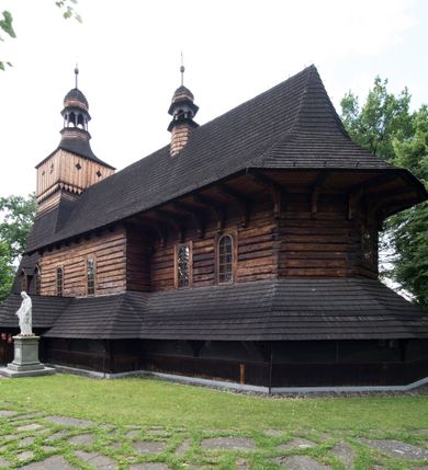 Zdjęcie nr 3: Drewniany kościół pw. św. Marcina w Jawiszowicach jest budowlą orientowaną, wzniesioną na zrąb. Do węższego prezbiterium zamkniętego trójbocznie przylega szersza nawa na rzucie zbliżonym do kwadratu. Od północy przy prezbiterium wybudowano zakrystię na planie wydłużonego prostokąta, a od zachodu wieżę w konstrukcji na słup na rzucie kwadratu. Zwieńczono ją izbicą z baniastym hełmem z latarnią. W przyziemiu wieży urządzono kruchtę. Nawę z prezbiterium nakryto jednokalenicowym dachem z więźbą w układzie storczykowym z przypustnicami (nadbitkami). W węższej części prezbiterialnej dach wsparty jest na trójkątnych zastrzałach widocznych na zewnątrz. Nad prezbiterium wznosi się sygnaturka w formie latarni z baniastym hełmem zwieńczonym krzyżem. Bryłę kościoła w całości otaczają arkadowe soboty z drewnianymi parapetami i z prześwitami wypełnionymi półprzeźroczystą pleksą. Na wysokości wejścia południowego do kościoła linię sobót wysunięto do przodu, dzięki czemu powstała pseudokruchta nakryta dachem siodłowym. Zarówno dach kościoła, jak i zakrystii, sobót oraz hełmy wieży i sygnaturki pokryte są gontem. Ściany nawy i prezbiterium utworzone z poziomo układanych bali przepruwają prostokątne okna z wpisanym łukiem półokrągłym, stanowiącym część stolarki okiennej. Na osi prezbiterium za ołtarzem głównym wycięto okulus. Wnętrze kościoła w nawie nakrywa płaski strop ze skośnym szalowaniem po bokach, a w prezbiterium pozorne sklepienie kolebkowe. Prezbiterium od nawy oddziela półokrągła tęcza z profilowaną belką, na której umieszczono grupę Ukrzyżowania. Całość wnętrza zdobi wielobarwna, ornamentalno-figuralna polichromia. Podłogę świątyni wyłożono kamiennymi płytami. W zachodniej części nawy urządzono chór muzyczny wsparty na dwóch drewnianych filarach z klatką schodową usytuowaną w południowo-zachodnim narożniku. Na chórze ustawiono prospekt organowy. Do wnętrza kościoła prowadzą dwa wejścia - od zachodu poprzez kruchtę w przyziemiu wieży oraz od południa z drewnianym portalem zamkniętym łukiem odcinkowym. Drewniany portal zamknięty łukiem odcinkowym prowadzi także z prezbiterium do zakrystii. Wypełniają go obite metalowymi płycinami i listwami drzwi. Własne wejście na zewnątrz posiada także zakrystia. Wnętrze prezbiterium w części wschodniej wypełnia architektoniczny ołtarz główny. Na ścianie północnej prezbiterium przy łuku tęczowym zawieszono ambonę, do której schody prowadzą z zakrystii. Pod skosem po obu stronach łuku tęczowego w narożnikach nawy ustawiono dwa ołtarze boczne, a pod chórem muzycznym dwa konfesjonały. W nawie stoją dwa rzędy ław kościelnych, a na jej ścianie północnej zawieszono na półeczkach feretrony procesyjne. Kościół otacza droga procesyjna wyłożona kamiennymi płytami, a cmentarz przykościelny zamyka drewniany parkan z dwiema bramkami wejściowymi.    