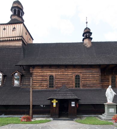 Zdjęcie nr 29: Drewniany kościół pw. św. Marcina w Jawiszowicach jest budowlą orientowaną, wzniesioną na zrąb. Do węższego prezbiterium zamkniętego trójbocznie przylega szersza nawa na rzucie zbliżonym do kwadratu. Od północy przy prezbiterium wybudowano zakrystię na planie wydłużonego prostokąta, a od zachodu wieżę w konstrukcji na słup na rzucie kwadratu. Zwieńczono ją izbicą z baniastym hełmem z latarnią. W przyziemiu wieży urządzono kruchtę. Nawę z prezbiterium nakryto jednokalenicowym dachem z więźbą w układzie storczykowym z przypustnicami (nadbitkami). W węższej części prezbiterialnej dach wsparty jest na trójkątnych zastrzałach widocznych na zewnątrz. Nad prezbiterium wznosi się sygnaturka w formie latarni z baniastym hełmem zwieńczonym krzyżem. Bryłę kościoła w całości otaczają arkadowe soboty z drewnianymi parapetami i z prześwitami wypełnionymi półprzeźroczystą pleksą. Na wysokości wejścia południowego do kościoła linię sobót wysunięto do przodu, dzięki czemu powstała pseudokruchta nakryta dachem siodłowym. Zarówno dach kościoła, jak i zakrystii, sobót oraz hełmy wieży i sygnaturki pokryte są gontem. Ściany nawy i prezbiterium utworzone z poziomo układanych bali przepruwają prostokątne okna z wpisanym łukiem półokrągłym, stanowiącym część stolarki okiennej. Na osi prezbiterium za ołtarzem głównym wycięto okulus. Wnętrze kościoła w nawie nakrywa płaski strop ze skośnym szalowaniem po bokach, a w prezbiterium pozorne sklepienie kolebkowe. Prezbiterium od nawy oddziela półokrągła tęcza z profilowaną belką, na której umieszczono grupę Ukrzyżowania. Całość wnętrza zdobi wielobarwna, ornamentalno-figuralna polichromia. Podłogę świątyni wyłożono kamiennymi płytami. W zachodniej części nawy urządzono chór muzyczny wsparty na dwóch drewnianych filarach z klatką schodową usytuowaną w południowo-zachodnim narożniku. Na chórze ustawiono prospekt organowy. Do wnętrza kościoła prowadzą dwa wejścia - od zachodu poprzez kruchtę w przyziemiu wieży oraz od południa z drewnianym portalem zamkniętym łukiem odcinkowym. Drewniany portal zamknięty łukiem odcinkowym prowadzi także z prezbiterium do zakrystii. Wypełniają go obite metalowymi płycinami i listwami drzwi. Własne wejście na zewnątrz posiada także zakrystia. Wnętrze prezbiterium w części wschodniej wypełnia architektoniczny ołtarz główny. Na ścianie północnej prezbiterium przy łuku tęczowym zawieszono ambonę, do której schody prowadzą z zakrystii. Pod skosem po obu stronach łuku tęczowego w narożnikach nawy ustawiono dwa ołtarze boczne, a pod chórem muzycznym dwa konfesjonały. W nawie stoją dwa rzędy ław kościelnych, a na jej ścianie północnej zawieszono na półeczkach feretrony procesyjne. Kościół otacza droga procesyjna wyłożona kamiennymi płytami, a cmentarz przykościelny zamyka drewniany parkan z dwiema bramkami wejściowymi.    