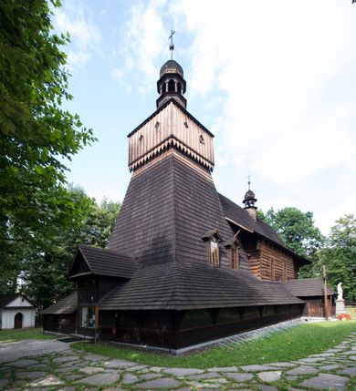 Zdjęcie nr 13: Drewniany kościół pw. św. Marcina w Jawiszowicach jest budowlą orientowaną, wzniesioną na zrąb. Do węższego prezbiterium zamkniętego trójbocznie przylega szersza nawa na rzucie zbliżonym do kwadratu. Od północy przy prezbiterium wybudowano zakrystię na planie wydłużonego prostokąta, a od zachodu wieżę w konstrukcji na słup na rzucie kwadratu. Zwieńczono ją izbicą z baniastym hełmem z latarnią. W przyziemiu wieży urządzono kruchtę. Nawę z prezbiterium nakryto jednokalenicowym dachem z więźbą w układzie storczykowym z przypustnicami (nadbitkami). W węższej części prezbiterialnej dach wsparty jest na trójkątnych zastrzałach widocznych na zewnątrz. Nad prezbiterium wznosi się sygnaturka w formie latarni z baniastym hełmem zwieńczonym krzyżem. Bryłę kościoła w całości otaczają arkadowe soboty z drewnianymi parapetami i z prześwitami wypełnionymi półprzeźroczystą pleksą. Na wysokości wejścia południowego do kościoła linię sobót wysunięto do przodu, dzięki czemu powstała pseudokruchta nakryta dachem siodłowym. Zarówno dach kościoła, jak i zakrystii, sobót oraz hełmy wieży i sygnaturki pokryte są gontem. Ściany nawy i prezbiterium utworzone z poziomo układanych bali przepruwają prostokątne okna z wpisanym łukiem półokrągłym, stanowiącym część stolarki okiennej. Na osi prezbiterium za ołtarzem głównym wycięto okulus. Wnętrze kościoła w nawie nakrywa płaski strop ze skośnym szalowaniem po bokach, a w prezbiterium pozorne sklepienie kolebkowe. Prezbiterium od nawy oddziela półokrągła tęcza z profilowaną belką, na której umieszczono grupę Ukrzyżowania. Całość wnętrza zdobi wielobarwna, ornamentalno-figuralna polichromia. Podłogę świątyni wyłożono kamiennymi płytami. W zachodniej części nawy urządzono chór muzyczny wsparty na dwóch drewnianych filarach z klatką schodową usytuowaną w południowo-zachodnim narożniku. Na chórze ustawiono prospekt organowy. Do wnętrza kościoła prowadzą dwa wejścia - od zachodu poprzez kruchtę w przyziemiu wieży oraz od południa z drewnianym portalem zamkniętym łukiem odcinkowym. Drewniany portal zamknięty łukiem odcinkowym prowadzi także z prezbiterium do zakrystii. Wypełniają go obite metalowymi płycinami i listwami drzwi. Własne wejście na zewnątrz posiada także zakrystia. Wnętrze prezbiterium w części wschodniej wypełnia architektoniczny ołtarz główny. Na ścianie północnej prezbiterium przy łuku tęczowym zawieszono ambonę, do której schody prowadzą z zakrystii. Pod skosem po obu stronach łuku tęczowego w narożnikach nawy ustawiono dwa ołtarze boczne, a pod chórem muzycznym dwa konfesjonały. W nawie stoją dwa rzędy ław kościelnych, a na jej ścianie północnej zawieszono na półeczkach feretrony procesyjne. Kościół otacza droga procesyjna wyłożona kamiennymi płytami, a cmentarz przykościelny zamyka drewniany parkan z dwiema bramkami wejściowymi.    