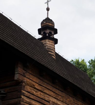 Zdjęcie nr 8: Drewniany kościół pw. św. Marcina w Jawiszowicach jest budowlą orientowaną, wzniesioną na zrąb. Do węższego prezbiterium zamkniętego trójbocznie przylega szersza nawa na rzucie zbliżonym do kwadratu. Od północy przy prezbiterium wybudowano zakrystię na planie wydłużonego prostokąta, a od zachodu wieżę w konstrukcji na słup na rzucie kwadratu. Zwieńczono ją izbicą z baniastym hełmem z latarnią. W przyziemiu wieży urządzono kruchtę. Nawę z prezbiterium nakryto jednokalenicowym dachem z więźbą w układzie storczykowym z przypustnicami (nadbitkami). W węższej części prezbiterialnej dach wsparty jest na trójkątnych zastrzałach widocznych na zewnątrz. Nad prezbiterium wznosi się sygnaturka w formie latarni z baniastym hełmem zwieńczonym krzyżem. Bryłę kościoła w całości otaczają arkadowe soboty z drewnianymi parapetami i z prześwitami wypełnionymi półprzeźroczystą pleksą. Na wysokości wejścia południowego do kościoła linię sobót wysunięto do przodu, dzięki czemu powstała pseudokruchta nakryta dachem siodłowym. Zarówno dach kościoła, jak i zakrystii, sobót oraz hełmy wieży i sygnaturki pokryte są gontem. Ściany nawy i prezbiterium utworzone z poziomo układanych bali przepruwają prostokątne okna z wpisanym łukiem półokrągłym, stanowiącym część stolarki okiennej. Na osi prezbiterium za ołtarzem głównym wycięto okulus. Wnętrze kościoła w nawie nakrywa płaski strop ze skośnym szalowaniem po bokach, a w prezbiterium pozorne sklepienie kolebkowe. Prezbiterium od nawy oddziela półokrągła tęcza z profilowaną belką, na której umieszczono grupę Ukrzyżowania. Całość wnętrza zdobi wielobarwna, ornamentalno-figuralna polichromia. Podłogę świątyni wyłożono kamiennymi płytami. W zachodniej części nawy urządzono chór muzyczny wsparty na dwóch drewnianych filarach z klatką schodową usytuowaną w południowo-zachodnim narożniku. Na chórze ustawiono prospekt organowy. Do wnętrza kościoła prowadzą dwa wejścia - od zachodu poprzez kruchtę w przyziemiu wieży oraz od południa z drewnianym portalem zamkniętym łukiem odcinkowym. Drewniany portal zamknięty łukiem odcinkowym prowadzi także z prezbiterium do zakrystii. Wypełniają go obite metalowymi płycinami i listwami drzwi. Własne wejście na zewnątrz posiada także zakrystia. Wnętrze prezbiterium w części wschodniej wypełnia architektoniczny ołtarz główny. Na ścianie północnej prezbiterium przy łuku tęczowym zawieszono ambonę, do której schody prowadzą z zakrystii. Pod skosem po obu stronach łuku tęczowego w narożnikach nawy ustawiono dwa ołtarze boczne, a pod chórem muzycznym dwa konfesjonały. W nawie stoją dwa rzędy ław kościelnych, a na jej ścianie północnej zawieszono na półeczkach feretrony procesyjne. Kościół otacza droga procesyjna wyłożona kamiennymi płytami, a cmentarz przykościelny zamyka drewniany parkan z dwiema bramkami wejściowymi.    