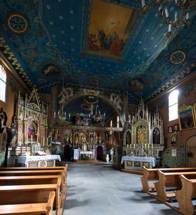 Zdjęcie nr 17: Drewniany kościół pw. św. Marcina w Jawiszowicach jest budowlą orientowaną, wzniesioną na zrąb. Do węższego prezbiterium zamkniętego trójbocznie przylega szersza nawa na rzucie zbliżonym do kwadratu. Od północy przy prezbiterium wybudowano zakrystię na planie wydłużonego prostokąta, a od zachodu wieżę w konstrukcji na słup na rzucie kwadratu. Zwieńczono ją izbicą z baniastym hełmem z latarnią. W przyziemiu wieży urządzono kruchtę. Nawę z prezbiterium nakryto jednokalenicowym dachem z więźbą w układzie storczykowym z przypustnicami (nadbitkami). W węższej części prezbiterialnej dach wsparty jest na trójkątnych zastrzałach widocznych na zewnątrz. Nad prezbiterium wznosi się sygnaturka w formie latarni z baniastym hełmem zwieńczonym krzyżem. Bryłę kościoła w całości otaczają arkadowe soboty z drewnianymi parapetami i z prześwitami wypełnionymi półprzeźroczystą pleksą. Na wysokości wejścia południowego do kościoła linię sobót wysunięto do przodu, dzięki czemu powstała pseudokruchta nakryta dachem siodłowym. Zarówno dach kościoła, jak i zakrystii, sobót oraz hełmy wieży i sygnaturki pokryte są gontem. Ściany nawy i prezbiterium utworzone z poziomo układanych bali przepruwają prostokątne okna z wpisanym łukiem półokrągłym, stanowiącym część stolarki okiennej. Na osi prezbiterium za ołtarzem głównym wycięto okulus. Wnętrze kościoła w nawie nakrywa płaski strop ze skośnym szalowaniem po bokach, a w prezbiterium pozorne sklepienie kolebkowe. Prezbiterium od nawy oddziela półokrągła tęcza z profilowaną belką, na której umieszczono grupę Ukrzyżowania. Całość wnętrza zdobi wielobarwna, ornamentalno-figuralna polichromia. Podłogę świątyni wyłożono kamiennymi płytami. W zachodniej części nawy urządzono chór muzyczny wsparty na dwóch drewnianych filarach z klatką schodową usytuowaną w południowo-zachodnim narożniku. Na chórze ustawiono prospekt organowy. Do wnętrza kościoła prowadzą dwa wejścia - od zachodu poprzez kruchtę w przyziemiu wieży oraz od południa z drewnianym portalem zamkniętym łukiem odcinkowym. Drewniany portal zamknięty łukiem odcinkowym prowadzi także z prezbiterium do zakrystii. Wypełniają go obite metalowymi płycinami i listwami drzwi. Własne wejście na zewnątrz posiada także zakrystia. Wnętrze prezbiterium w części wschodniej wypełnia architektoniczny ołtarz główny. Na ścianie północnej prezbiterium przy łuku tęczowym zawieszono ambonę, do której schody prowadzą z zakrystii. Pod skosem po obu stronach łuku tęczowego w narożnikach nawy ustawiono dwa ołtarze boczne, a pod chórem muzycznym dwa konfesjonały. W nawie stoją dwa rzędy ław kościelnych, a na jej ścianie północnej zawieszono na półeczkach feretrony procesyjne. Kościół otacza droga procesyjna wyłożona kamiennymi płytami, a cmentarz przykościelny zamyka drewniany parkan z dwiema bramkami wejściowymi.    