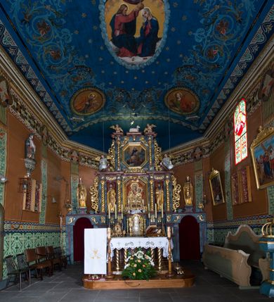 Zdjęcie nr 18: Drewniany kościół pw. św. Marcina w Jawiszowicach jest budowlą orientowaną, wzniesioną na zrąb. Do węższego prezbiterium zamkniętego trójbocznie przylega szersza nawa na rzucie zbliżonym do kwadratu. Od północy przy prezbiterium wybudowano zakrystię na planie wydłużonego prostokąta, a od zachodu wieżę w konstrukcji na słup na rzucie kwadratu. Zwieńczono ją izbicą z baniastym hełmem z latarnią. W przyziemiu wieży urządzono kruchtę. Nawę z prezbiterium nakryto jednokalenicowym dachem z więźbą w układzie storczykowym z przypustnicami (nadbitkami). W węższej części prezbiterialnej dach wsparty jest na trójkątnych zastrzałach widocznych na zewnątrz. Nad prezbiterium wznosi się sygnaturka w formie latarni z baniastym hełmem zwieńczonym krzyżem. Bryłę kościoła w całości otaczają arkadowe soboty z drewnianymi parapetami i z prześwitami wypełnionymi półprzeźroczystą pleksą. Na wysokości wejścia południowego do kościoła linię sobót wysunięto do przodu, dzięki czemu powstała pseudokruchta nakryta dachem siodłowym. Zarówno dach kościoła, jak i zakrystii, sobót oraz hełmy wieży i sygnaturki pokryte są gontem. Ściany nawy i prezbiterium utworzone z poziomo układanych bali przepruwają prostokątne okna z wpisanym łukiem półokrągłym, stanowiącym część stolarki okiennej. Na osi prezbiterium za ołtarzem głównym wycięto okulus. Wnętrze kościoła w nawie nakrywa płaski strop ze skośnym szalowaniem po bokach, a w prezbiterium pozorne sklepienie kolebkowe. Prezbiterium od nawy oddziela półokrągła tęcza z profilowaną belką, na której umieszczono grupę Ukrzyżowania. Całość wnętrza zdobi wielobarwna, ornamentalno-figuralna polichromia. Podłogę świątyni wyłożono kamiennymi płytami. W zachodniej części nawy urządzono chór muzyczny wsparty na dwóch drewnianych filarach z klatką schodową usytuowaną w południowo-zachodnim narożniku. Na chórze ustawiono prospekt organowy. Do wnętrza kościoła prowadzą dwa wejścia - od zachodu poprzez kruchtę w przyziemiu wieży oraz od południa z drewnianym portalem zamkniętym łukiem odcinkowym. Drewniany portal zamknięty łukiem odcinkowym prowadzi także z prezbiterium do zakrystii. Wypełniają go obite metalowymi płycinami i listwami drzwi. Własne wejście na zewnątrz posiada także zakrystia. Wnętrze prezbiterium w części wschodniej wypełnia architektoniczny ołtarz główny. Na ścianie północnej prezbiterium przy łuku tęczowym zawieszono ambonę, do której schody prowadzą z zakrystii. Pod skosem po obu stronach łuku tęczowego w narożnikach nawy ustawiono dwa ołtarze boczne, a pod chórem muzycznym dwa konfesjonały. W nawie stoją dwa rzędy ław kościelnych, a na jej ścianie północnej zawieszono na półeczkach feretrony procesyjne. Kościół otacza droga procesyjna wyłożona kamiennymi płytami, a cmentarz przykościelny zamyka drewniany parkan z dwiema bramkami wejściowymi.    