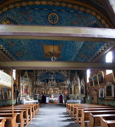 Zdjęcie nr 10: Drewniany kościół pw. św. Marcina w Jawiszowicach jest budowlą orientowaną, wzniesioną na zrąb. Do węższego prezbiterium zamkniętego trójbocznie przylega szersza nawa na rzucie zbliżonym do kwadratu. Od północy przy prezbiterium wybudowano zakrystię na planie wydłużonego prostokąta, a od zachodu wieżę w konstrukcji na słup na rzucie kwadratu. Zwieńczono ją izbicą z baniastym hełmem z latarnią. W przyziemiu wieży urządzono kruchtę. Nawę z prezbiterium nakryto jednokalenicowym dachem z więźbą w układzie storczykowym z przypustnicami (nadbitkami). W węższej części prezbiterialnej dach wsparty jest na trójkątnych zastrzałach widocznych na zewnątrz. Nad prezbiterium wznosi się sygnaturka w formie latarni z baniastym hełmem zwieńczonym krzyżem. Bryłę kościoła w całości otaczają arkadowe soboty z drewnianymi parapetami i z prześwitami wypełnionymi półprzeźroczystą pleksą. Na wysokości wejścia południowego do kościoła linię sobót wysunięto do przodu, dzięki czemu powstała pseudokruchta nakryta dachem siodłowym. Zarówno dach kościoła, jak i zakrystii, sobót oraz hełmy wieży i sygnaturki pokryte są gontem. Ściany nawy i prezbiterium utworzone z poziomo układanych bali przepruwają prostokątne okna z wpisanym łukiem półokrągłym, stanowiącym część stolarki okiennej. Na osi prezbiterium za ołtarzem głównym wycięto okulus. Wnętrze kościoła w nawie nakrywa płaski strop ze skośnym szalowaniem po bokach, a w prezbiterium pozorne sklepienie kolebkowe. Prezbiterium od nawy oddziela półokrągła tęcza z profilowaną belką, na której umieszczono grupę Ukrzyżowania. Całość wnętrza zdobi wielobarwna, ornamentalno-figuralna polichromia. Podłogę świątyni wyłożono kamiennymi płytami. W zachodniej części nawy urządzono chór muzyczny wsparty na dwóch drewnianych filarach z klatką schodową usytuowaną w południowo-zachodnim narożniku. Na chórze ustawiono prospekt organowy. Do wnętrza kościoła prowadzą dwa wejścia - od zachodu poprzez kruchtę w przyziemiu wieży oraz od południa z drewnianym portalem zamkniętym łukiem odcinkowym. Drewniany portal zamknięty łukiem odcinkowym prowadzi także z prezbiterium do zakrystii. Wypełniają go obite metalowymi płycinami i listwami drzwi. Własne wejście na zewnątrz posiada także zakrystia. Wnętrze prezbiterium w części wschodniej wypełnia architektoniczny ołtarz główny. Na ścianie północnej prezbiterium przy łuku tęczowym zawieszono ambonę, do której schody prowadzą z zakrystii. Pod skosem po obu stronach łuku tęczowego w narożnikach nawy ustawiono dwa ołtarze boczne, a pod chórem muzycznym dwa konfesjonały. W nawie stoją dwa rzędy ław kościelnych, a na jej ścianie północnej zawieszono na półeczkach feretrony procesyjne. Kościół otacza droga procesyjna wyłożona kamiennymi płytami, a cmentarz przykościelny zamyka drewniany parkan z dwiema bramkami wejściowymi.    