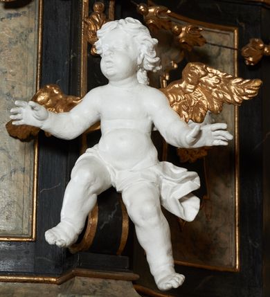 Zdjęcie nr 4: Ambona przyścienna, wisząca z dostępem od strony wewnętrznej klatki schodowej usytuowanej w murze kościoła. Kosz na planie kwadratu o wklęsłych bokach, wypukłym froncie i ściętych narożach, z podwieszeniem w formie stylizowanego, odwróconego stożka zakończonego wolutą. Kosz w narożach ujęty pilastrami o trzonach w formie wolut, dźwigającymi belkowanie parapetu. Ścianki dekorowane płycinami z polami o obrysie utworzonym z linii wklęsło-wypukłej wzbogaconej odcinkami prostymi; w płycinach uskrzydlone główki anielskie. W partii belkowania parapetu front ambony zdobiony muszlą, ujętą kwiatowymi girlandami, na tle pilastrów dwa putta. Zaplecek ujęty pilastrami oraz spływami wolutowymi, dźwigającymi belkowanie. W polu drzwiczki w formie stojącego prostokąta, dekorowane płyciną o wykroju ukształtowanym na bazie falistej, wklęsło-wypukłej linii. Powyżej dwie uskrzydlone główki anielskie. Baldachim płaski, na planie analogicznym do kosza ambony, opasany profilowanym gzymsem, dźwigającym przerwany, wolutowy przyczółek, flankowany przez dwa putta. Całość zwieńczona glorią promienistą z rzeźbioną gołębicą Ducha Świętego.

 Struktura marmoryzowana, w kolorze brązowo-szarym, ciemnoszarym i niebieskim, profile i ornamenty złocone i srebrzone.