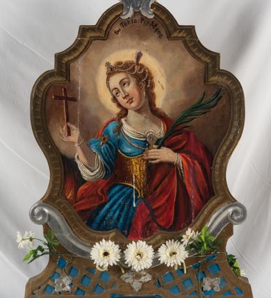 Zdjęcie nr 3: Feretron na podstawie ozdobionej kratką regencyjną, w profilowanej ramie o falistym wykroju zwieńczonej liściem akantu. Struktura obramienia jest w kolorze niebieskim oraz złocona i srebrzona. Na awersie św. Notburga ukazana w stroju służącej: długiej biało-czerwonej sukni i niebieskim gorsecie, zwrócona w lewo, ze wzrokiem skierowanym ku górze. Twarz pełna, wyraziste rysy i podbródek. Długie, jasnobrązowe, zebrane do tyłu włosy opadają na plecy. Święta wznosi do góry zgięte w łokciach ręce. U dołu, po lewej stronie kompozycji snopek zboża, natomiast w prawym dolnym rogu święta ukazana przy pracy w polu. W tle pejzaż wiejski z obniżoną linią horyzontu i niebem w odcieniach żółci i pomarańczy. Po lewej stronie kompozycji, na wysokosci głowy świętej sierp unoszący się w powietrzu, u góry para uskrzydlonych główek anielskich. Na rewersie feretronu wizerunek św. Tekli ukazanej w półpostaci, frontalnie z głową skierowaną w prawo. Twarz pełna, nos prosty, wargi pełne, oczy szeroko otwarte; włosy kręcone, jasne, długie, z wplecionymi sznurami pereł. Święta ubrana jest w dwie suknie – spodnią białą, wierzchnią niebieską, złoty gorset i czerwony płaszcz. W prawej, uniesionej ręce trzyma krzyż, lewą rękę, w której trzyma liść palmy przyciska do piersi. 

W górnej partii obrazu napis czarną farbą „Sw(ięta) Tekla P(anna) i Męcz(ennica)”.