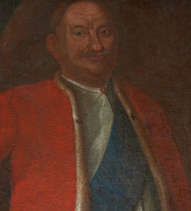 Zdjęcie nr 14: Obraz w kształcie stojącego prostokąta ujętego dekoracyjną ramą z uszakami, motywem paludamentum oraz wyobrażeniem Orderu Orła Białego przedstawia całopostaciową sylwetkę Franciszka Szwracenberg-Czernego. Twarz, zwróconego w trzech czwartych w prawo mężczyzny charakteryzują pozbawione idealizacji cechy portretowe o długim, zaokrąglonym na końcu nosie, lekko podkrążonych oczach, szerokich ustach, spiczastych wąsach, bruzdach na czole oraz wydatnym podbródku. Ubrany jest on w długi, biały żupan przewiązany czerwonym pasem kontuszowym oraz czerwoną, podszytą futrem gronostajowym delię. Przez piersi przewieszona jest błękitna szarfa będąca fragmentem garnituru Orderu Orła Białego. U lewego boku przypięta jest szabla. Prawą rękę wspiera na biodrze, lewą, w której trzyma rysunek fasady kościoła, na niewielkim stoliku o wygiętych nogach. W tle, po lewej stronie kompozycji widoczna jest granatowa, obszyta złotą frędzlą kotara.     