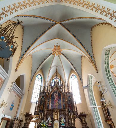 Zdjęcie nr 12: Neogotycki, murowany kościół św. Andrzeja Apostoła w Osieku jest pięcioprzęsłową świątynią salową z wyodrębnionym, trójbocznie zamkniętym prezbiterium od północy i czworoboczną wieżą od południa. Od zachodu do prezbiterium i nawy przylega zakrystia z przedsionkiem, a od wschodu czworoboczna kaplica Najświętszego Serca Pana Jezusa. Ściany elewacji zewnętrznych artykułują wysokie przypory wyznaczające przęsła, licowane czerwoną i żółtą cegłą, układaną we wzór ornamentalny. Każde z przęseł przeprute jest dużym, ostrołukowym oknem, dekorowanym przy ostrołuku ceglaną opaską. Górne odcinki pomiędzy przyporami zdobi poziomy, ceglany fryz kostkowy, zaś pod dachem ceglany gzyms koronujący. Elewacja południowa z wieżą jest trójosiowa. Oś środkową wyznacza dwupoziomowa, czworoboczna wieża wchodząca w ostatnie przęsło nawy. Flankują ją wysokie przypory podobnie jak na elewacjach bocznych licowane czerwoną i żółtą cegłą. Pierwszy poziom dekoruje rozbudowany, ceglany, ostrołukowy portal, ponad którym przepruto ostrołukowe okno. Ponad oknem z ceglaną opaską przy ostrołuku, schodzącą na poziomy, ceglany fryz kostkowy znajduje się okulus z maswerkiem z motywem rybiego pęcherza. W portalu mocno zaakcentowano ostrołukowy tympanon wypełniony maswerkiem ze sztucznego kamienia z motywami czteroliścia. Wieżę wieńczy ostrosłupowy hełm z krzyżem, pokryty blachą miedzianą, oparty na zmniejszonym, czworobocznym piętrze dzwonniczym tworzącym jej drugi poziom. W jego narożach usytuowano ceglane przypory ze sterczynami, zaś ściany boczne przepruto ostrołukowym oknem z ceglaną opaską przy ostrołuku, wypełnionym drewnianą żaluzją, wieńcząc je trójkątnymi szczytami ze sterczynami. Pole trójkątnych szczytów zawierają okrągłe tarcze zegarowe. Osie boczne elewacji wyznaczają podłużne, ostrołukowe okna z ceglanymi opaskami na wysokości ostrołuku oraz umieszczone poniżej mniejsze ostrołukowe okna doświetlające przyziemię z klatką schodową i nawę od zachodu. Wnętrze zostało nakryte sklepieniem krzyżowym. Kolejne przęsła rozdzielają ostrołukowe gurty spływające na przyścienne półfilary ustawione na cokołach i zwieńczone fazowanymi opaskami. Niższe, jednoprzęsłowe prezbiterium oddziela od nawy ostrołukowy łuk tęczowy. Przylegająca do prezbiterium od wschodu kaplica także otwiera się do wnętrze kościoła ostrołukową arkadą. W drugim przęśle usytuowano naprzeciw siebie ostrołukowe drzwi boczne. W prezbiterium ustawiono ołtarz główny, a po obu stronach łuku tęczowego dwa ołtarze boczne. Na zachodniej ścianie prezbiterium przy tęczy zawieszono ambonę. Także w kaplicy bocznej ustawiono nastawę ołtarzową. Nawę wypełniają dwa rzędy drewnianych ławek oraz dwa konfesjonały. W ostatnim przęśle, po obu stronach wchodzącej w nie wieży, urządzono chór muzyczny, na który prowadzi klatka schodowa z wejściem w przyziemiu wieży. Chór wsparto na trzech ostrołukowych arkadach. Podłogę w nawie i prezbiterium wyłożono posadzką z kolorowego granitu.   