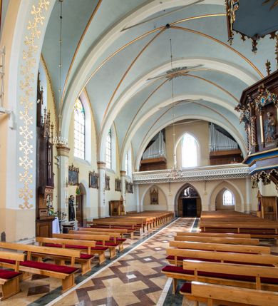 Zdjęcie nr 13: Neogotycki, murowany kościół św. Andrzeja Apostoła w Osieku jest pięcioprzęsłową świątynią salową z wyodrębnionym, trójbocznie zamkniętym prezbiterium od północy i czworoboczną wieżą od południa. Od zachodu do prezbiterium i nawy przylega zakrystia z przedsionkiem, a od wschodu czworoboczna kaplica Najświętszego Serca Pana Jezusa. Ściany elewacji zewnętrznych artykułują wysokie przypory wyznaczające przęsła, licowane czerwoną i żółtą cegłą, układaną we wzór ornamentalny. Każde z przęseł przeprute jest dużym, ostrołukowym oknem, dekorowanym przy ostrołuku ceglaną opaską. Górne odcinki pomiędzy przyporami zdobi poziomy, ceglany fryz kostkowy, zaś pod dachem ceglany gzyms koronujący. Elewacja południowa z wieżą jest trójosiowa. Oś środkową wyznacza dwupoziomowa, czworoboczna wieża wchodząca w ostatnie przęsło nawy. Flankują ją wysokie przypory podobnie jak na elewacjach bocznych licowane czerwoną i żółtą cegłą. Pierwszy poziom dekoruje rozbudowany, ceglany, ostrołukowy portal, ponad którym przepruto ostrołukowe okno. Ponad oknem z ceglaną opaską przy ostrołuku, schodzącą na poziomy, ceglany fryz kostkowy znajduje się okulus z maswerkiem z motywem rybiego pęcherza. W portalu mocno zaakcentowano ostrołukowy tympanon wypełniony maswerkiem ze sztucznego kamienia z motywami czteroliścia. Wieżę wieńczy ostrosłupowy hełm z krzyżem, pokryty blachą miedzianą, oparty na zmniejszonym, czworobocznym piętrze dzwonniczym tworzącym jej drugi poziom. W jego narożach usytuowano ceglane przypory ze sterczynami, zaś ściany boczne przepruto ostrołukowym oknem z ceglaną opaską przy ostrołuku, wypełnionym drewnianą żaluzją, wieńcząc je trójkątnymi szczytami ze sterczynami. Pole trójkątnych szczytów zawierają okrągłe tarcze zegarowe. Osie boczne elewacji wyznaczają podłużne, ostrołukowe okna z ceglanymi opaskami na wysokości ostrołuku oraz umieszczone poniżej mniejsze ostrołukowe okna doświetlające przyziemię z klatką schodową i nawę od zachodu. Wnętrze zostało nakryte sklepieniem krzyżowym. Kolejne przęsła rozdzielają ostrołukowe gurty spływające na przyścienne półfilary ustawione na cokołach i zwieńczone fazowanymi opaskami. Niższe, jednoprzęsłowe prezbiterium oddziela od nawy ostrołukowy łuk tęczowy. Przylegająca do prezbiterium od wschodu kaplica także otwiera się do wnętrze kościoła ostrołukową arkadą. W drugim przęśle usytuowano naprzeciw siebie ostrołukowe drzwi boczne. W prezbiterium ustawiono ołtarz główny, a po obu stronach łuku tęczowego dwa ołtarze boczne. Na zachodniej ścianie prezbiterium przy tęczy zawieszono ambonę. Także w kaplicy bocznej ustawiono nastawę ołtarzową. Nawę wypełniają dwa rzędy drewnianych ławek oraz dwa konfesjonały. W ostatnim przęśle, po obu stronach wchodzącej w nie wieży, urządzono chór muzyczny, na który prowadzi klatka schodowa z wejściem w przyziemiu wieży. Chór wsparto na trzech ostrołukowych arkadach. Podłogę w nawie i prezbiterium wyłożono posadzką z kolorowego granitu.   