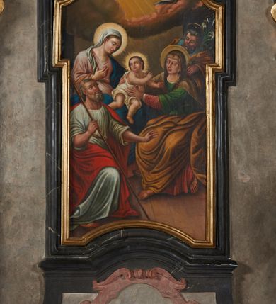 Zdjęcie nr 10: Obraz w formie stojącego prostokąta wklęsłego u dołu, zamkniętego łukiem odcinkowym nadwieszonym z uskokiem, z uszakami po bokach. W lewej części obrazu ukazana jest siedząca Maria zwrócona w lewo. Ubrana jest w różową suknię, niebieski płaszcz i białą chustę na głowie. Prawą rękę trzyma na piersi, lewą obejmuje siedzące na jej kolanach Dzieciątko okryte białą szatą. Obok niej, w prawej części obrazu siedzi skierowana do niej św. Anna ubrana w czerwona i zieloną suknię, brązowy płaszcz i brązową chustę na głowie. Pochylona kobieta obiema rękami ujmuje Dzieciątko. Za św. Anną stoi nachylony św. Józef, ubrany w niebieską suknię i brązowy płaszcz. W dłoni trzyma lilię. Na pierwszym planie, po lewej stronie kompozycji siedzi spoglądając na Dzieciatko św. Joachim. Mężczyzna ma na sobie białą suknię i czerwony płaszcz, w prawej ręce trzyma laskę. Głowy Marii, Jezusa i sw. Anny okalają nimby, natomiast św. Józefa i św. Joachima aureole. U dołu obrazu widoczna jest posadzka, natomiast w tle rozświetlone niebo z promieniami słonecznymi oraz rozchodzące się obłoki z uskrzydlonymi główkami anielskimi w prawym, górnym rogu.