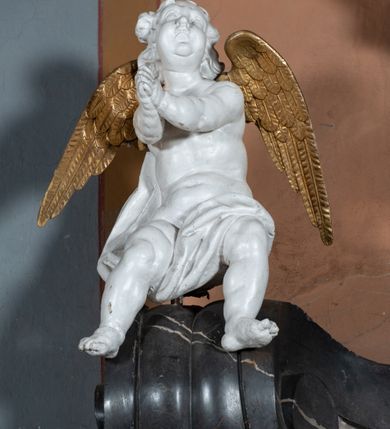 Zdjęcie nr 7: Nastawa ołtarza stiukowa, architektoniczna, jednoosiowa, jednokondygnacyjna, o wklęsłym licu, ze zwieńczeniem oraz osadzona na wysokim cokole. Ołtarz drewniany, sarkofagowy z drewnianą, silnie wysuniętą mensą. Retabulum ujęte jest parą zdwojonych pilastrów o trzonach dekorowanych konsolkami i kampanulami na froncie, dźwigających przerwane belkowanie. W polu środkowym umieszczono obraz św. Mikołaja ujęty profilowaną ramą w formie stojącego prostokąta zamkniętego łukiem odcinkowym, nadwieszonym z uskokiem i uszakami po bokach, wklęsłego u spodu. Poniżej obrazu znajduje się płycina ujęta spływami wolutowymi, zamknięta fragmentem gzymsu w formie łuku odcinkowego. W jej polu jest kartusz o fantazyjnym wykroju. Zwieńczenie ujęto parą spływów wolutowych i zamknięto fragmentem wklęsło-wypukłego gzymsu, na którym jest płomienisty wazon. Na końcach spływów wolutowych znajduje się para siedzących putt.  
Pole zwieńczenia wypełniają płaskorzeźbione obłoki z uskrzydlonymi główkami anielskimi oraz ukazana na ich tle promienista gloria z monogramem maryjnym pośrodku. Struktura retabulum jest marmoryzowana w kolorze szaro-brązowym i ciemnoszarym, ze złoconymi i srebrzonymi detalami.
