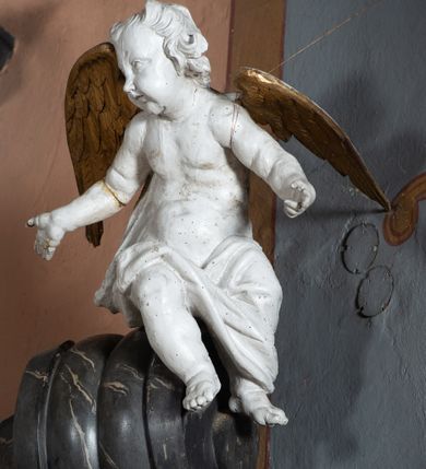 Zdjęcie nr 11: Nastawa ołtarza stiukowa, architektoniczna, jednoosiowa, jednokondygnacyjna, o wklęsłym licu, ze zwieńczeniem oraz osadzona na wysokim cokole. Ołtarz drewniany, sarkofagowy z drewnianą, silnie wysuniętą mensą. Retabulum ujęte jest parą zdwojonych pilastrów o trzonach dekorowanych konsolkami i kampanulami na froncie, dźwigających przerwane belkowanie. W polu środkowym umieszczono obraz św. Mikołaja ujęty profilowaną ramą w formie stojącego prostokąta zamkniętego łukiem odcinkowym, nadwieszonym z uskokiem i uszakami po bokach, wklęsłego u spodu. Poniżej obrazu znajduje się płycina ujęta spływami wolutowymi, zamknięta fragmentem gzymsu w formie łuku odcinkowego. W jej polu jest kartusz o fantazyjnym wykroju. Zwieńczenie ujęto parą spływów wolutowych i zamknięto fragmentem wklęsło-wypukłego gzymsu, na którym jest płomienisty wazon. Na końcach spływów wolutowych znajduje się para siedzących putt.  
Pole zwieńczenia wypełniają płaskorzeźbione obłoki z uskrzydlonymi główkami anielskimi oraz ukazana na ich tle promienista gloria z monogramem maryjnym pośrodku. Struktura retabulum jest marmoryzowana w kolorze szaro-brązowym i ciemnoszarym, ze złoconymi i srebrzonymi detalami.
