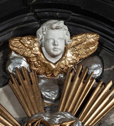 Zdjęcie nr 30: Nastawa ołtarza stiukowa, architektoniczna, jednoosiowa, jednokondygnacyjna, o wklęsłym licu, ze zwieńczeniem oraz osadzona na wysokim cokole. Ołtarz drewniany, sarkofagowy z drewnianą, silnie wysuniętą mensą. Retabulum ujęte jest parą zdwojonych pilastrów o trzonach dekorowanych konsolkami i kampanulami na froncie, dźwigających przerwane belkowanie. W polu środkowym umieszczono obraz św. Mikołaja ujęty profilowaną ramą w formie stojącego prostokąta zamkniętego łukiem odcinkowym, nadwieszonym z uskokiem i uszakami po bokach, wklęsłego u spodu. Poniżej obrazu znajduje się płycina ujęta spływami wolutowymi, zamknięta fragmentem gzymsu w formie łuku odcinkowego. W jej polu jest kartusz o fantazyjnym wykroju. Zwieńczenie ujęto parą spływów wolutowych i zamknięto fragmentem wklęsło-wypukłego gzymsu, na którym jest płomienisty wazon. Na końcach spływów wolutowych znajduje się para siedzących putt.  
Pole zwieńczenia wypełniają płaskorzeźbione obłoki z uskrzydlonymi główkami anielskimi oraz ukazana na ich tle promienista gloria z monogramem maryjnym pośrodku. Struktura retabulum jest marmoryzowana w kolorze szaro-brązowym i ciemnoszarym, ze złoconymi i srebrzonymi detalami.
