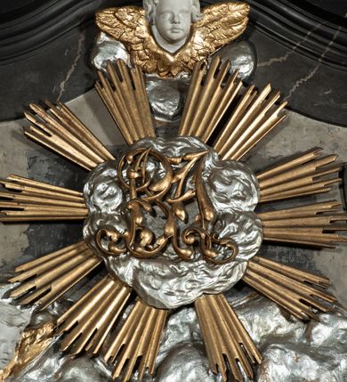 Zdjęcie nr 29: Nastawa ołtarza stiukowa, architektoniczna, jednoosiowa, jednokondygnacyjna, o wklęsłym licu, ze zwieńczeniem oraz osadzona na wysokim cokole. Ołtarz drewniany, sarkofagowy z drewnianą, silnie wysuniętą mensą. Retabulum ujęte jest parą zdwojonych pilastrów o trzonach dekorowanych konsolkami i kampanulami na froncie, dźwigających przerwane belkowanie. W polu środkowym umieszczono obraz św. Mikołaja ujęty profilowaną ramą w formie stojącego prostokąta zamkniętego łukiem odcinkowym, nadwieszonym z uskokiem i uszakami po bokach, wklęsłego u spodu. Poniżej obrazu znajduje się płycina ujęta spływami wolutowymi, zamknięta fragmentem gzymsu w formie łuku odcinkowego. W jej polu jest kartusz o fantazyjnym wykroju. Zwieńczenie ujęto parą spływów wolutowych i zamknięto fragmentem wklęsło-wypukłego gzymsu, na którym jest płomienisty wazon. Na końcach spływów wolutowych znajduje się para siedzących putt.  
Pole zwieńczenia wypełniają płaskorzeźbione obłoki z uskrzydlonymi główkami anielskimi oraz ukazana na ich tle promienista gloria z monogramem maryjnym pośrodku. Struktura retabulum jest marmoryzowana w kolorze szaro-brązowym i ciemnoszarym, ze złoconymi i srebrzonymi detalami.
