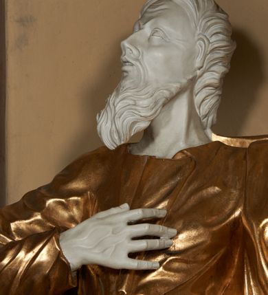 Zdjęcie nr 5: Figura ustawiona na na kwadratowej podstawie, drążona z tyłu, przedstawia stojącego św. Joachima, wyobrażonego w całej postaci. zwróconego nieznacznie w prawo, z uniesioną ku górze głową. Prawa ręka św. Joachima spoczywa na piersi, w lewej, lekko zgiętej w łokciu i odsuniętej w bok trzyma szufle pasterską. Twarz jest pociągła, wychudzona, z długim zarostem i o wyrazistych rysach z silnie uwypuklonymi kośćmi policzkowymi, liniami łuków brwiowych, wąskim nosem, małymi, rozchylonymi, pełnymi ustami z uniesioną górną wargą oraz dużymi, głęboko osadzonymi oczami spoglądającymi w górę. Krótkie, lekko falowane włosy układają się w regularne pukle. Smukłą i wydłużoną sylwetkę świętego osłania przylegająca do ciała, długa, drapowana suknia przepasana w talii oraz narzucony na plecy i opadający wzdłuż boków płaszcz z fragmentem tkaniny zasłaniającym częściowo lewe udo. Kolorystyka odsłoniętych partii ciała utrzymana jest w bieli, szaty złocone, drzewiec, na którym osadzona jest szufla srebrzony.