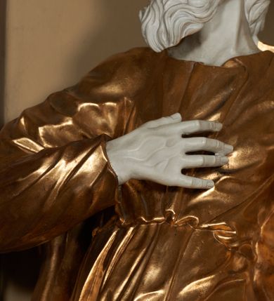 Zdjęcie nr 3: Figura ustawiona na na kwadratowej podstawie, drążona z tyłu, przedstawia stojącego św. Joachima, wyobrażonego w całej postaci. zwróconego nieznacznie w prawo, z uniesioną ku górze głową. Prawa ręka św. Joachima spoczywa na piersi, w lewej, lekko zgiętej w łokciu i odsuniętej w bok trzyma szufle pasterską. Twarz jest pociągła, wychudzona, z długim zarostem i o wyrazistych rysach z silnie uwypuklonymi kośćmi policzkowymi, liniami łuków brwiowych, wąskim nosem, małymi, rozchylonymi, pełnymi ustami z uniesioną górną wargą oraz dużymi, głęboko osadzonymi oczami spoglądającymi w górę. Krótkie, lekko falowane włosy układają się w regularne pukle. Smukłą i wydłużoną sylwetkę świętego osłania przylegająca do ciała, długa, drapowana suknia przepasana w talii oraz narzucony na plecy i opadający wzdłuż boków płaszcz z fragmentem tkaniny zasłaniającym częściowo lewe udo. Kolorystyka odsłoniętych partii ciała utrzymana jest w bieli, szaty złocone, drzewiec, na którym osadzona jest szufla srebrzony.