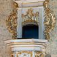 Zdjęcie nr 1: Ambona, przyścienna, wisząca, z jednobiegowymi schodami od strony prezbiterium. Kosz w formie czworoboku o ściętych narożach ze spływami wolutowymi. Ścianki kosza zdobione są nieregularną ramą z ornamentu rocaille&#039;owego. W płycinie czołowej (południowej) płaskorzeźba Siewcy. Woluty zdobione ornamentami kwiatowymi w formie girland podtrzymują mocno wysunięte, wyłamane na ich osi belkowanie. Kosz od dołu zakończony jest stożkiem ujętym czterema wolutami, dekorowanymi motywami roślinnymi, zakończony roacille’ową szyszką. Zaplecek w kształcie stojącego prostokąta, ujęty dwoma kanelowanymi pilastrami podtrzymującymi belkowanie wyłamane nad osią główną. W dolnej części zaplecka drzwiczki zamknięte łukiem odcinkowym, a w górnej płaskorzeźbiona dekoracja rocaille’owa. Po bokach zaplecka ażurowe rocaille’owe uszy. Baldachim powtarzający rzut kosza z lambrekinem podwieszonym u dołu i zamknięty silnie wysuniętym gzymsem. Zwieńczenie uformowane z czterech wolut spiętych w kabłąk, na którego szczycie na niskim kwadratowym cokole ustawiona jest figura Michała Archanioła depczącego szatana. W podniebieniu gołębica Ducha Świętego na tle promienistej glorii. Polichromia w kolorze białym, ornamentyka złocona, gołębica srebrzona, podniebienie baldachimu malowane na niebiesko.
