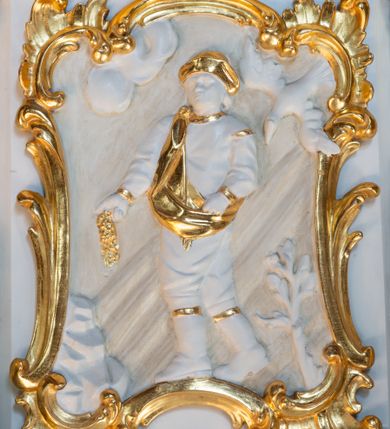 Zdjęcie nr 2: Ambona, przyścienna, wisząca, z jednobiegowymi schodami od strony prezbiterium. Kosz w formie czworoboku o ściętych narożach ze spływami wolutowymi. Ścianki kosza zdobione są nieregularną ramą z ornamentu rocaille'owego. W płycinie czołowej (południowej) płaskorzeźba Siewcy. Woluty zdobione ornamentami kwiatowymi w formie girland podtrzymują mocno wysunięte, wyłamane na ich osi belkowanie. Kosz od dołu zakończony jest stożkiem ujętym czterema wolutami, dekorowanymi motywami roślinnymi, zakończony roacille’ową szyszką. Zaplecek w kształcie stojącego prostokąta, ujęty dwoma kanelowanymi pilastrami podtrzymującymi belkowanie wyłamane nad osią główną. W dolnej części zaplecka drzwiczki zamknięte łukiem odcinkowym, a w górnej płaskorzeźbiona dekoracja rocaille’owa. Po bokach zaplecka ażurowe rocaille’owe uszy. Baldachim powtarzający rzut kosza z lambrekinem podwieszonym u dołu i zamknięty silnie wysuniętym gzymsem. Zwieńczenie uformowane z czterech wolut spiętych w kabłąk, na którego szczycie na niskim kwadratowym cokole ustawiona jest figura Michała Archanioła depczącego szatana. W podniebieniu gołębica Ducha Świętego na tle promienistej glorii. Polichromia w kolorze białym, ornamentyka złocona, gołębica srebrzona, podniebienie baldachimu malowane na niebiesko.
