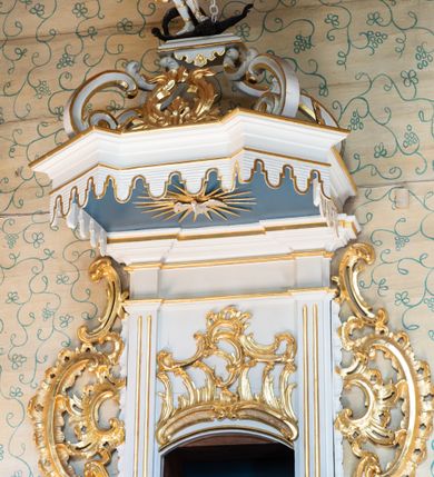 Zdjęcie nr 3: Ambona, przyścienna, wisząca, z jednobiegowymi schodami od strony prezbiterium. Kosz w formie czworoboku o ściętych narożach ze spływami wolutowymi. Ścianki kosza zdobione są nieregularną ramą z ornamentu rocaille'owego. W płycinie czołowej (południowej) płaskorzeźba Siewcy. Woluty zdobione ornamentami kwiatowymi w formie girland podtrzymują mocno wysunięte, wyłamane na ich osi belkowanie. Kosz od dołu zakończony jest stożkiem ujętym czterema wolutami, dekorowanymi motywami roślinnymi, zakończony roacille’ową szyszką. Zaplecek w kształcie stojącego prostokąta, ujęty dwoma kanelowanymi pilastrami podtrzymującymi belkowanie wyłamane nad osią główną. W dolnej części zaplecka drzwiczki zamknięte łukiem odcinkowym, a w górnej płaskorzeźbiona dekoracja rocaille’owa. Po bokach zaplecka ażurowe rocaille’owe uszy. Baldachim powtarzający rzut kosza z lambrekinem podwieszonym u dołu i zamknięty silnie wysuniętym gzymsem. Zwieńczenie uformowane z czterech wolut spiętych w kabłąk, na którego szczycie na niskim kwadratowym cokole ustawiona jest figura Michała Archanioła depczącego szatana. W podniebieniu gołębica Ducha Świętego na tle promienistej glorii. Polichromia w kolorze białym, ornamentyka złocona, gołębica srebrzona, podniebienie baldachimu malowane na niebiesko.
