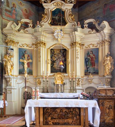 Zdjęcie nr 29: Kościół drewniany, orientowany, jednonawowy o konstrukcji zrębowej, oszalowany. Prezbiterium kwadratowe o wielobocznym zamknięciu z zakrystią od północy. Nawa szersza, prawie kwadratowa, przy niej od północy kaplica i składzik później dostawiony; od południa i od zachodu kruchty. Korpus nakryty dachem dwuspadowym, jednokalenicowym, z barokową wieżyczką na sygnaturkę na kalenicy; składzik nakryty dachem pulpitowym. Wewnątrz stropy kasetonowe. Otwór tęczy o profilowanym łuku półkolistym podwyższonym; belka profilowana, na niej grupa Ukrzyżowania. Chór muzyczny wsparty na dwóch słupach. Kaplica otwarta do nawy półkolistą arkadą. Troje drzwi o ozdobnych obramieniach uszatych, schodkowatych i uszato-schodkowatych, ze starymi okuciami. Wieża nowa, izbicowa o pochyłych ścianach, zwieńczona ostrosłupowym hełmem.
