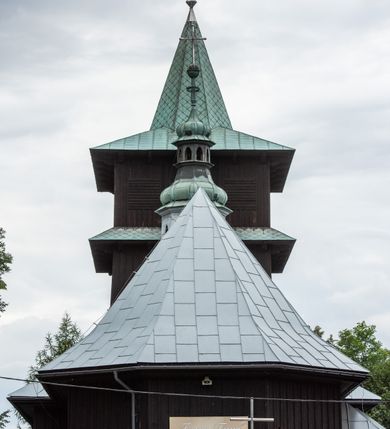 Zdjęcie nr 21: Kościół drewniany, orientowany, jednonawowy o konstrukcji zrębowej, oszalowany. Prezbiterium kwadratowe o wielobocznym zamknięciu z zakrystią od północy. Nawa szersza, prawie kwadratowa, przy niej od północy kaplica i składzik później dostawiony; od południa i od zachodu kruchty. Korpus nakryty dachem dwuspadowym, jednokalenicowym, z barokową wieżyczką na sygnaturkę na kalenicy; składzik nakryty dachem pulpitowym. Wewnątrz stropy kasetonowe. Otwór tęczy o profilowanym łuku półkolistym podwyższonym; belka profilowana, na niej grupa Ukrzyżowania. Chór muzyczny wsparty na dwóch słupach. Kaplica otwarta do nawy półkolistą arkadą. Troje drzwi o ozdobnych obramieniach uszatych, schodkowatych i uszato-schodkowatych, ze starymi okuciami. Wieża nowa, izbicowa o pochyłych ścianach, zwieńczona ostrosłupowym hełmem.
