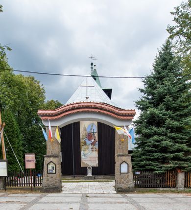 Zdjęcie nr 16: Kościół drewniany, orientowany, jednonawowy o konstrukcji zrębowej, oszalowany. Prezbiterium kwadratowe o wielobocznym zamknięciu z zakrystią od północy. Nawa szersza, prawie kwadratowa, przy niej od północy kaplica i składzik później dostawiony; od południa i od zachodu kruchty. Korpus nakryty dachem dwuspadowym, jednokalenicowym, z barokową wieżyczką na sygnaturkę na kalenicy; składzik nakryty dachem pulpitowym. Wewnątrz stropy kasetonowe. Otwór tęczy o profilowanym łuku półkolistym podwyższonym; belka profilowana, na niej grupa Ukrzyżowania. Chór muzyczny wsparty na dwóch słupach. Kaplica otwarta do nawy półkolistą arkadą. Troje drzwi o ozdobnych obramieniach uszatych, schodkowatych i uszato-schodkowatych, ze starymi okuciami. Wieża nowa, izbicowa o pochyłych ścianach, zwieńczona ostrosłupowym hełmem.
