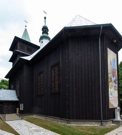 Zdjęcie nr 10: Kościół drewniany, orientowany, jednonawowy o konstrukcji zrębowej, oszalowany. Prezbiterium kwadratowe o wielobocznym zamknięciu z zakrystią od północy. Nawa szersza, prawie kwadratowa, przy niej od północy kaplica i składzik później dostawiony; od południa i od zachodu kruchty. Korpus nakryty dachem dwuspadowym, jednokalenicowym, z barokową wieżyczką na sygnaturkę na kalenicy; składzik nakryty dachem pulpitowym. Wewnątrz stropy kasetonowe. Otwór tęczy o profilowanym łuku półkolistym podwyższonym; belka profilowana, na niej grupa Ukrzyżowania. Chór muzyczny wsparty na dwóch słupach. Kaplica otwarta do nawy półkolistą arkadą. Troje drzwi o ozdobnych obramieniach uszatych, schodkowatych i uszato-schodkowatych, ze starymi okuciami. Wieża nowa, izbicowa o pochyłych ścianach, zwieńczona ostrosłupowym hełmem.
