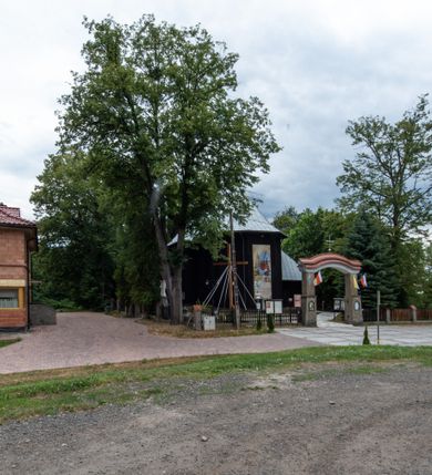 Zdjęcie nr 40: Kościół drewniany, orientowany, jednonawowy o konstrukcji zrębowej, oszalowany. Prezbiterium kwadratowe o wielobocznym zamknięciu z zakrystią od północy. Nawa szersza, prawie kwadratowa, przy niej od północy kaplica i składzik później dostawiony; od południa i od zachodu kruchty. Korpus nakryty dachem dwuspadowym, jednokalenicowym, z barokową wieżyczką na sygnaturkę na kalenicy; składzik nakryty dachem pulpitowym. Wewnątrz stropy kasetonowe. Otwór tęczy o profilowanym łuku półkolistym podwyższonym; belka profilowana, na niej grupa Ukrzyżowania. Chór muzyczny wsparty na dwóch słupach. Kaplica otwarta do nawy półkolistą arkadą. Troje drzwi o ozdobnych obramieniach uszatych, schodkowatych i uszato-schodkowatych, ze starymi okuciami. Wieża nowa, izbicowa o pochyłych ścianach, zwieńczona ostrosłupowym hełmem.
