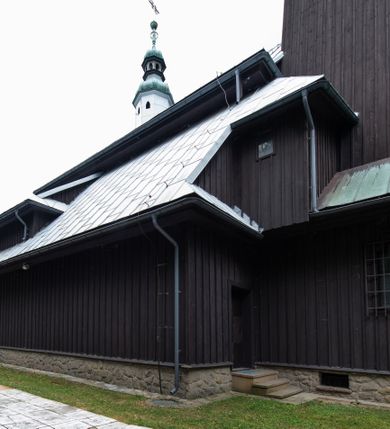 Zdjęcie nr 45: Kościół drewniany, orientowany, jednonawowy o konstrukcji zrębowej, oszalowany. Prezbiterium kwadratowe o wielobocznym zamknięciu z zakrystią od północy. Nawa szersza, prawie kwadratowa, przy niej od północy kaplica i składzik później dostawiony; od południa i od zachodu kruchty. Korpus nakryty dachem dwuspadowym, jednokalenicowym, z barokową wieżyczką na sygnaturkę na kalenicy; składzik nakryty dachem pulpitowym. Wewnątrz stropy kasetonowe. Otwór tęczy o profilowanym łuku półkolistym podwyższonym; belka profilowana, na niej grupa Ukrzyżowania. Chór muzyczny wsparty na dwóch słupach. Kaplica otwarta do nawy półkolistą arkadą. Troje drzwi o ozdobnych obramieniach uszatych, schodkowatych i uszato-schodkowatych, ze starymi okuciami. Wieża nowa, izbicowa o pochyłych ścianach, zwieńczona ostrosłupowym hełmem.
