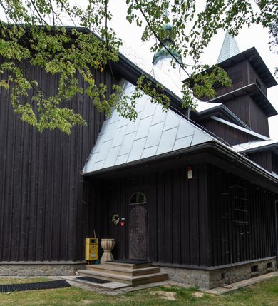 Zdjęcie nr 7: Kościół drewniany, orientowany, jednonawowy o konstrukcji zrębowej, oszalowany. Prezbiterium kwadratowe o wielobocznym zamknięciu z zakrystią od północy. Nawa szersza, prawie kwadratowa, przy niej od północy kaplica i składzik później dostawiony; od południa i od zachodu kruchty. Korpus nakryty dachem dwuspadowym, jednokalenicowym, z barokową wieżyczką na sygnaturkę na kalenicy; składzik nakryty dachem pulpitowym. Wewnątrz stropy kasetonowe. Otwór tęczy o profilowanym łuku półkolistym podwyższonym; belka profilowana, na niej grupa Ukrzyżowania. Chór muzyczny wsparty na dwóch słupach. Kaplica otwarta do nawy półkolistą arkadą. Troje drzwi o ozdobnych obramieniach uszatych, schodkowatych i uszato-schodkowatych, ze starymi okuciami. Wieża nowa, izbicowa o pochyłych ścianach, zwieńczona ostrosłupowym hełmem.
