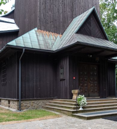 Zdjęcie nr 43: Kościół drewniany, orientowany, jednonawowy o konstrukcji zrębowej, oszalowany. Prezbiterium kwadratowe o wielobocznym zamknięciu z zakrystią od północy. Nawa szersza, prawie kwadratowa, przy niej od północy kaplica i składzik później dostawiony; od południa i od zachodu kruchty. Korpus nakryty dachem dwuspadowym, jednokalenicowym, z barokową wieżyczką na sygnaturkę na kalenicy; składzik nakryty dachem pulpitowym. Wewnątrz stropy kasetonowe. Otwór tęczy o profilowanym łuku półkolistym podwyższonym; belka profilowana, na niej grupa Ukrzyżowania. Chór muzyczny wsparty na dwóch słupach. Kaplica otwarta do nawy półkolistą arkadą. Troje drzwi o ozdobnych obramieniach uszatych, schodkowatych i uszato-schodkowatych, ze starymi okuciami. Wieża nowa, izbicowa o pochyłych ścianach, zwieńczona ostrosłupowym hełmem.
