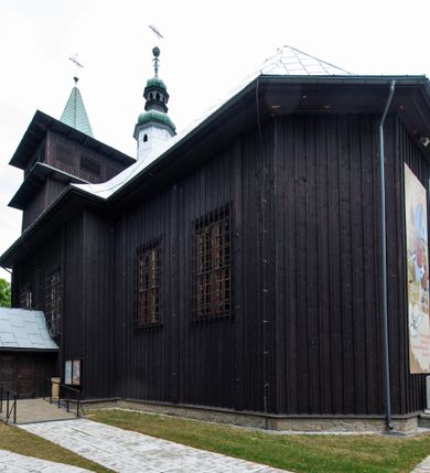 Zdjęcie nr 9: Kościół drewniany, orientowany, jednonawowy o konstrukcji zrębowej, oszalowany. Prezbiterium kwadratowe o wielobocznym zamknięciu z zakrystią od północy. Nawa szersza, prawie kwadratowa, przy niej od północy kaplica i składzik później dostawiony; od południa i od zachodu kruchty. Korpus nakryty dachem dwuspadowym, jednokalenicowym, z barokową wieżyczką na sygnaturkę na kalenicy; składzik nakryty dachem pulpitowym. Wewnątrz stropy kasetonowe. Otwór tęczy o profilowanym łuku półkolistym podwyższonym; belka profilowana, na niej grupa Ukrzyżowania. Chór muzyczny wsparty na dwóch słupach. Kaplica otwarta do nawy półkolistą arkadą. Troje drzwi o ozdobnych obramieniach uszatych, schodkowatych i uszato-schodkowatych, ze starymi okuciami. Wieża nowa, izbicowa o pochyłych ścianach, zwieńczona ostrosłupowym hełmem.
