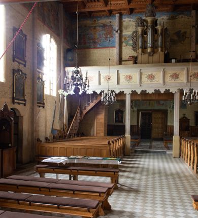 Zdjęcie nr 36: Kościół drewniany, orientowany, jednonawowy o konstrukcji zrębowej, oszalowany. Prezbiterium kwadratowe o wielobocznym zamknięciu z zakrystią od północy. Nawa szersza, prawie kwadratowa, przy niej od północy kaplica i składzik później dostawiony; od południa i od zachodu kruchty. Korpus nakryty dachem dwuspadowym, jednokalenicowym, z barokową wieżyczką na sygnaturkę na kalenicy; składzik nakryty dachem pulpitowym. Wewnątrz stropy kasetonowe. Otwór tęczy o profilowanym łuku półkolistym podwyższonym; belka profilowana, na niej grupa Ukrzyżowania. Chór muzyczny wsparty na dwóch słupach. Kaplica otwarta do nawy półkolistą arkadą. Troje drzwi o ozdobnych obramieniach uszatych, schodkowatych i uszato-schodkowatych, ze starymi okuciami. Wieża nowa, izbicowa o pochyłych ścianach, zwieńczona ostrosłupowym hełmem.
