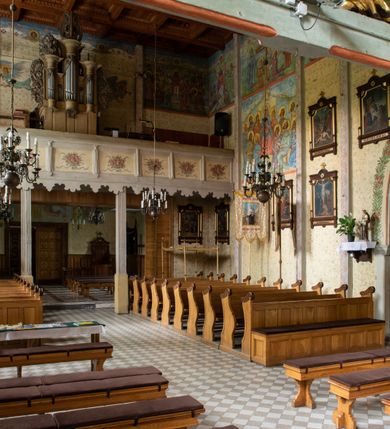 Zdjęcie nr 34: Kościół drewniany, orientowany, jednonawowy o konstrukcji zrębowej, oszalowany. Prezbiterium kwadratowe o wielobocznym zamknięciu z zakrystią od północy. Nawa szersza, prawie kwadratowa, przy niej od północy kaplica i składzik później dostawiony; od południa i od zachodu kruchty. Korpus nakryty dachem dwuspadowym, jednokalenicowym, z barokową wieżyczką na sygnaturkę na kalenicy; składzik nakryty dachem pulpitowym. Wewnątrz stropy kasetonowe. Otwór tęczy o profilowanym łuku półkolistym podwyższonym; belka profilowana, na niej grupa Ukrzyżowania. Chór muzyczny wsparty na dwóch słupach. Kaplica otwarta do nawy półkolistą arkadą. Troje drzwi o ozdobnych obramieniach uszatych, schodkowatych i uszato-schodkowatych, ze starymi okuciami. Wieża nowa, izbicowa o pochyłych ścianach, zwieńczona ostrosłupowym hełmem.
