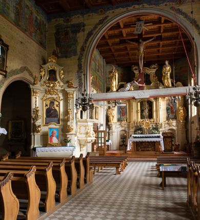 Zdjęcie nr 30: Kościół drewniany, orientowany, jednonawowy o konstrukcji zrębowej, oszalowany. Prezbiterium kwadratowe o wielobocznym zamknięciu z zakrystią od północy. Nawa szersza, prawie kwadratowa, przy niej od północy kaplica i składzik później dostawiony; od południa i od zachodu kruchty. Korpus nakryty dachem dwuspadowym, jednokalenicowym, z barokową wieżyczką na sygnaturkę na kalenicy; składzik nakryty dachem pulpitowym. Wewnątrz stropy kasetonowe. Otwór tęczy o profilowanym łuku półkolistym podwyższonym; belka profilowana, na niej grupa Ukrzyżowania. Chór muzyczny wsparty na dwóch słupach. Kaplica otwarta do nawy półkolistą arkadą. Troje drzwi o ozdobnych obramieniach uszatych, schodkowatych i uszato-schodkowatych, ze starymi okuciami. Wieża nowa, izbicowa o pochyłych ścianach, zwieńczona ostrosłupowym hełmem.
