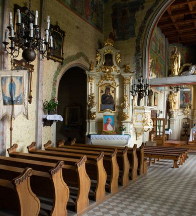 Zdjęcie nr 37: Kościół drewniany, orientowany, jednonawowy o konstrukcji zrębowej, oszalowany. Prezbiterium kwadratowe o wielobocznym zamknięciu z zakrystią od północy. Nawa szersza, prawie kwadratowa, przy niej od północy kaplica i składzik później dostawiony; od południa i od zachodu kruchty. Korpus nakryty dachem dwuspadowym, jednokalenicowym, z barokową wieżyczką na sygnaturkę na kalenicy; składzik nakryty dachem pulpitowym. Wewnątrz stropy kasetonowe. Otwór tęczy o profilowanym łuku półkolistym podwyższonym; belka profilowana, na niej grupa Ukrzyżowania. Chór muzyczny wsparty na dwóch słupach. Kaplica otwarta do nawy półkolistą arkadą. Troje drzwi o ozdobnych obramieniach uszatych, schodkowatych i uszato-schodkowatych, ze starymi okuciami. Wieża nowa, izbicowa o pochyłych ścianach, zwieńczona ostrosłupowym hełmem.
