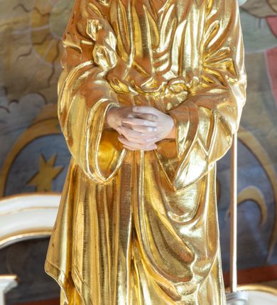 Zdjęcie nr 12: Łuk tęczowy o półkolistym wykroju, na profilowanej belce zdobionej pośrodku ryzowaną rozetą ustawiona grupa Ukrzyżowania. W centrum krucyfiks, po prawej św. Jan Ewangelista, po lewej Matka Boska i św. Maria Magdalena obejmująca krzyż. Chrystus przybity do krzyża trzema gwoździami, sylwetka w delikatnym zwisie, z głową pochyloną delikatnie w dół, o sztywnym układzie sylwetki z zaznaczonymi śladami męki. Perizonium w formie tkaniny przewiązanej na prawym biodrze ze zwisem wzdłuż prawego uda. Twarz podłużna, okolona zarostem; włosy długie spływające na prawe ramię w silnie skręcone pukle, na głowie zielona korona cierniowa złożona z dwóch przeplatających się gałązek. Nad głową Chrystusa biały titulus z napisem: „I(ESUS) N(AZARENUS) R(EX) I(UDAEORUM)”. Krzyż prosty, gładki o ramionach zakończonych gzymsikami. Po lewej stronie krucyfiksu rzeźba św. Marii Magdaleny ukazana w pozycji klęczącej, pochylonej do przodu, obejmująca dłońmi krzyż. Święta jest ubrana w długą, srebrzoną suknię, odsłaniającą nagie ramiona, przewiązaną w talii. Twarz szeroka, delikatnie otwarte usta, małe oczy i długi nos. Głowę okalają długie, ciemne włosy, spływające na plecy. Za nią ustawiona jest rzeźba Matki Boskiej w delikatnym kontrapoście, z prawą nogą ugiętą w kolanie, ze splecionymi na wysokości piersi rękami. Maria jest ubrana w długą, złoconą suknię oraz złocony płaszcz założony na głowę i spływający wzdłuż sylwetki. Twarz szeroka, z wyraźnie zaznaczonym podbródkiem, wzrok skierowany na krucyfiks, zmarszczone brwi. Po prawej stronie rzeźba św. Jana Ewangelisty, ukazanego w postawie stojącej, zwróconego w trzech czwartych w prawo, z rękami splecionymi na wysokości pasa. Twarz owalna, małe usta, długi i wąski nos, wzrok skierowany ku górze, zmarszczone brwi. Włosy ciemne, bujne, spływające na plecy. Święty ubrany jest w długą, złoconą suknię z długimi rękawami. Rzeźby ustawione są na niskich, zielonych cokolikach. Polichromia w odsłoniętych partiach ciała naturalistyczna, detale złocone i srebrzone. 
