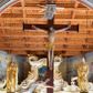Zdjęcie nr 1: Łuk tęczowy o półkolistym wykroju, na profilowanej belce zdobionej pośrodku ryzowaną rozetą ustawiona grupa Ukrzyżowania. W centrum krucyfiks, po prawej św. Jan Ewangelista, po lewej Matka Boska i św. Maria Magdalena obejmująca krzyż. Chrystus przybity do krzyża trzema gwoździami, sylwetka w delikatnym zwisie, z głową pochyloną delikatnie w dół, o sztywnym układzie sylwetki z zaznaczonymi śladami męki. Perizonium w formie tkaniny przewiązanej na prawym biodrze ze zwisem wzdłuż prawego uda. Twarz podłużna, okolona zarostem; włosy długie spływające na prawe ramię w silnie skręcone pukle, na głowie zielona korona cierniowa złożona z dwóch przeplatających się gałązek. Nad głową Chrystusa biały titulus z napisem: „I(ESUS) N(AZARENUS) R(EX) I(UDAEORUM)”. Krzyż prosty, gładki o ramionach zakończonych gzymsikami. Po lewej stronie krucyfiksu rzeźba św. Marii Magdaleny ukazana w pozycji klęczącej, pochylonej do przodu, obejmująca dłońmi krzyż. Święta jest ubrana w długą, srebrzoną suknię, odsłaniającą nagie ramiona, przewiązaną w talii. Twarz szeroka, delikatnie otwarte usta, małe oczy i długi nos. Głowę okalają długie, ciemne włosy, spływające na plecy. Za nią ustawiona jest rzeźba Matki Boskiej w delikatnym kontrapoście, z prawą nogą ugiętą w kolanie, ze splecionymi na wysokości piersi rękami. Maria jest ubrana w długą, złoconą suknię oraz złocony płaszcz założony na głowę i spływający wzdłuż sylwetki. Twarz szeroka, z wyraźnie zaznaczonym podbródkiem, wzrok skierowany na krucyfiks, zmarszczone brwi. Po prawej stronie rzeźba św. Jana Ewangelisty, ukazanego w postawie stojącej, zwróconego w trzech czwartych w prawo, z rękami splecionymi na wysokości pasa. Twarz owalna, małe usta, długi i wąski nos, wzrok skierowany ku górze, zmarszczone brwi. Włosy ciemne, bujne, spływające na plecy. Święty ubrany jest w długą, złoconą suknię z długimi rękawami. Rzeźby ustawione są na niskich, zielonych cokolikach. Polichromia w odsłoniętych partiach ciała naturalistyczna, detale złocone i srebrzone. 
