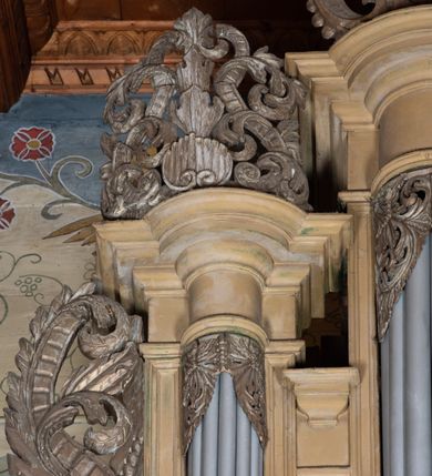 Zdjęcie nr 6: Organy architektoniczne, pięcioosiowe na wysokiej podstawie i niewielkim cokole, trójwieżyczkowe. Wieżyczki boczne niższe od środkowej, wszystkie z półokrągłymi ryzalitami, z prostokątnymi i wypukłymi prześwitami na piszczałki, dekorowanymi w górnych narożach akantem, zakończone fryzem i gzymsem oraz ornamentalnymi szczytami utworzonymi z akantu, karbowanej wstęgi, kampanul i muszli; ryzality u spodu z podwieszonymi kampanulami i muszlą. Szczyt środkowej wieżyczki utworzony z ornamentu małżowinowo-chrząstkowego. Pomiędzy wieżyczkami dwie najniższe osie z prześwitami na piszczałki w formie stojącego prostokąta, zakończone fragmentami gzymsu. Organy ujęte uszami utworzonymi z akantu i karbowanej wstęgi. Struktura polichromowana w całości w kolorze ciemnobeżowym, ornamenty złocone.